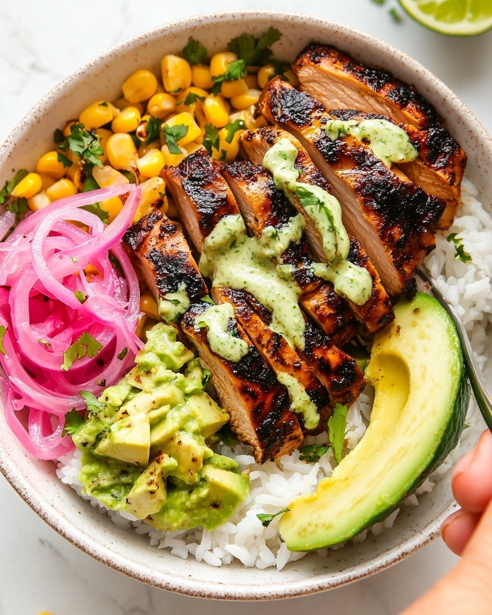 Caramelized BBQ Chicken Thighs in the Oven, oven BBQ chicken thighs recipe, easy baked BBQ chicken thighs, juicy oven grilled chicken, flavorful baked chicken thighs A white bowl filled with a base layer of white rice and small pieces of yellow corn scattered around. On top, there are slices of grilled dark brown chicken with a slightly charred texture, drizzled with a creamy pale green sauce. To one side, there are bright pink pickled onions in thin rings, while on the opposite side, a few slices of light green avocado rest near a lime wedge. Shredded pale green cabbage is layered next to the avocado. The dish is sprinkled with small bits of fresh green herbs. A silver fork is placed on the chicken, and a woman's hand is reaching towards the bowl from the bottom right corner. The bowl sits on a white marbled surface.