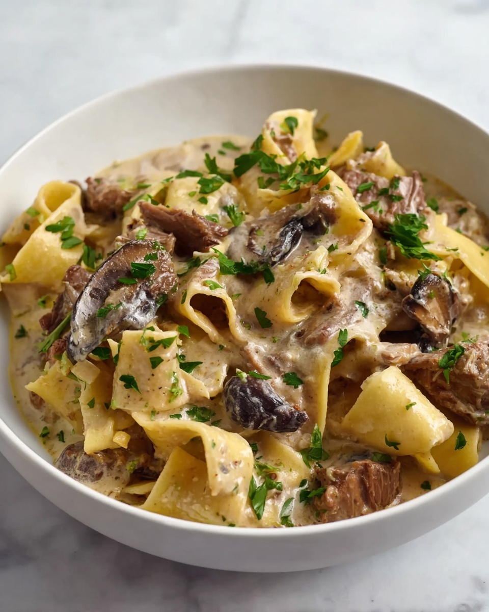 A white bowl filled with wide, flat pasta noodles twisted and folded, layered with pieces of brown cooked meat and dark, sliced mushrooms. The pasta and meat are covered in a creamy light beige sauce with tiny flecks of herbs. Bright green parsley leaves are scattered across the dish, adding a fresh pop of color. The bowl sits on a white marbled surface. photo taken with an iphone --ar 4:5 --v 7