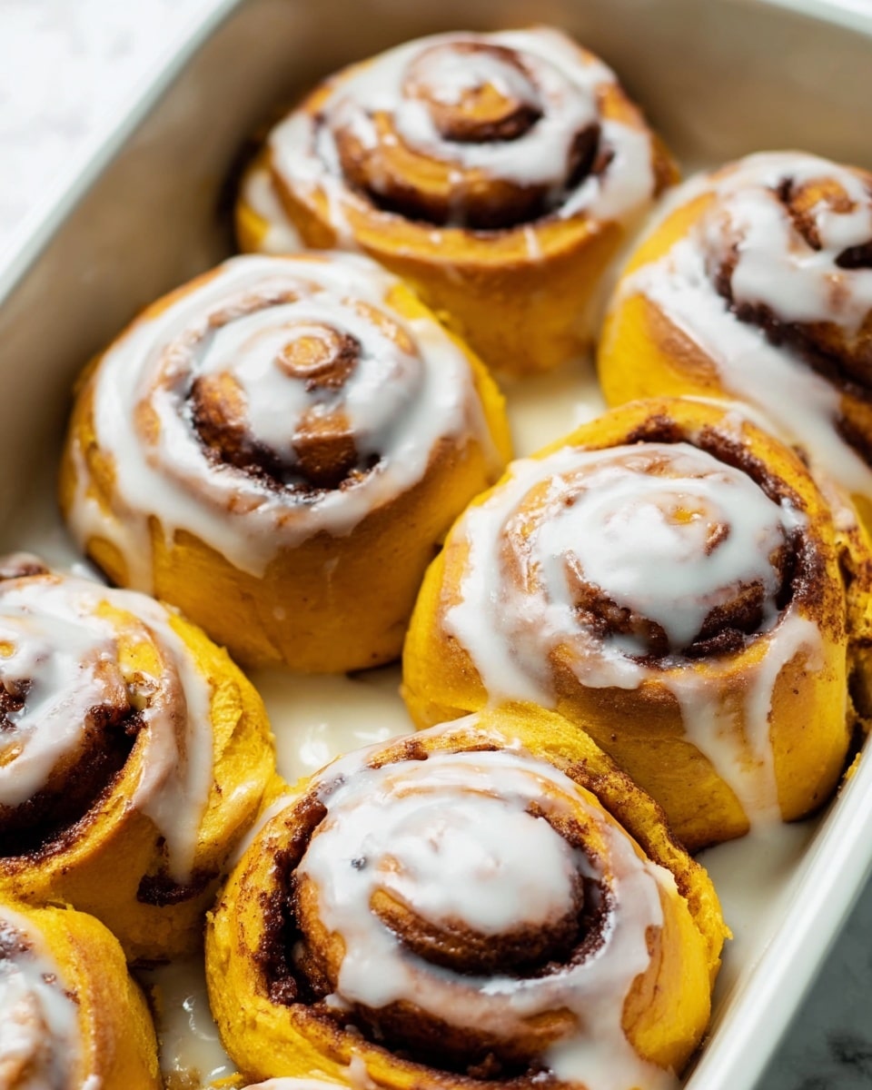 A group of three cinnamon rolls are shown resting on a black wire cooling rack. Each roll has a golden brown dough base with visible swirls filled with dark brown cinnamon and chopped pecans, adding a crunchy texture. A glossy white icing is drizzled unevenly over the top parts of the rolls, melting slightly down the sides. The background features a white marbled surface, enhancing the warm colors of the rolls. The photo is taken with an iphone --ar 4:5 --v 7