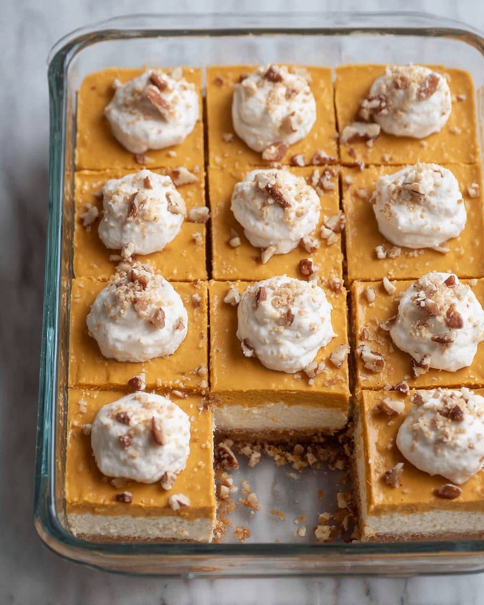 A glass rectangular dish filled with a pumpkin-colored dessert cut into nine even square pieces. Each square has one small white whipped cream dollop with a sprinkle of crushed nuts on top. One square is missing, revealing two layers inside: a thick white creamy layer on the bottom and a slightly thicker pumpkin-colored layer on top, smooth in texture. Some crushed nuts are scattered on the orange layer. The dish is placed on a white marbled surface. Photo taken with an iphone --ar 4:5 --v 7