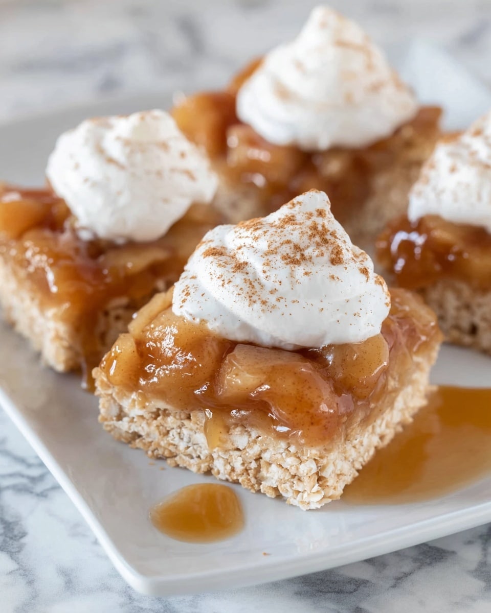 The image shows three square pieces of light brown crispy treats arranged on a white plate with a white marbled surface underneath. Each treat has three layers: the bottom layer is a crunchy, light brown crispy base; the middle layer features a shiny, amber-brown apple topping with visible apple chunks covered in syrup; and the top layer is a dollop of smooth white whipped cream sprinkled with a light dusting of cinnamon. The syrup from the apple topping slightly drips onto the plate, adding a glossy texture to the scene. The focus is close up, highlighting the textures and colors clearly. Photo taken with an iphone --ar 4:5 --v 7
