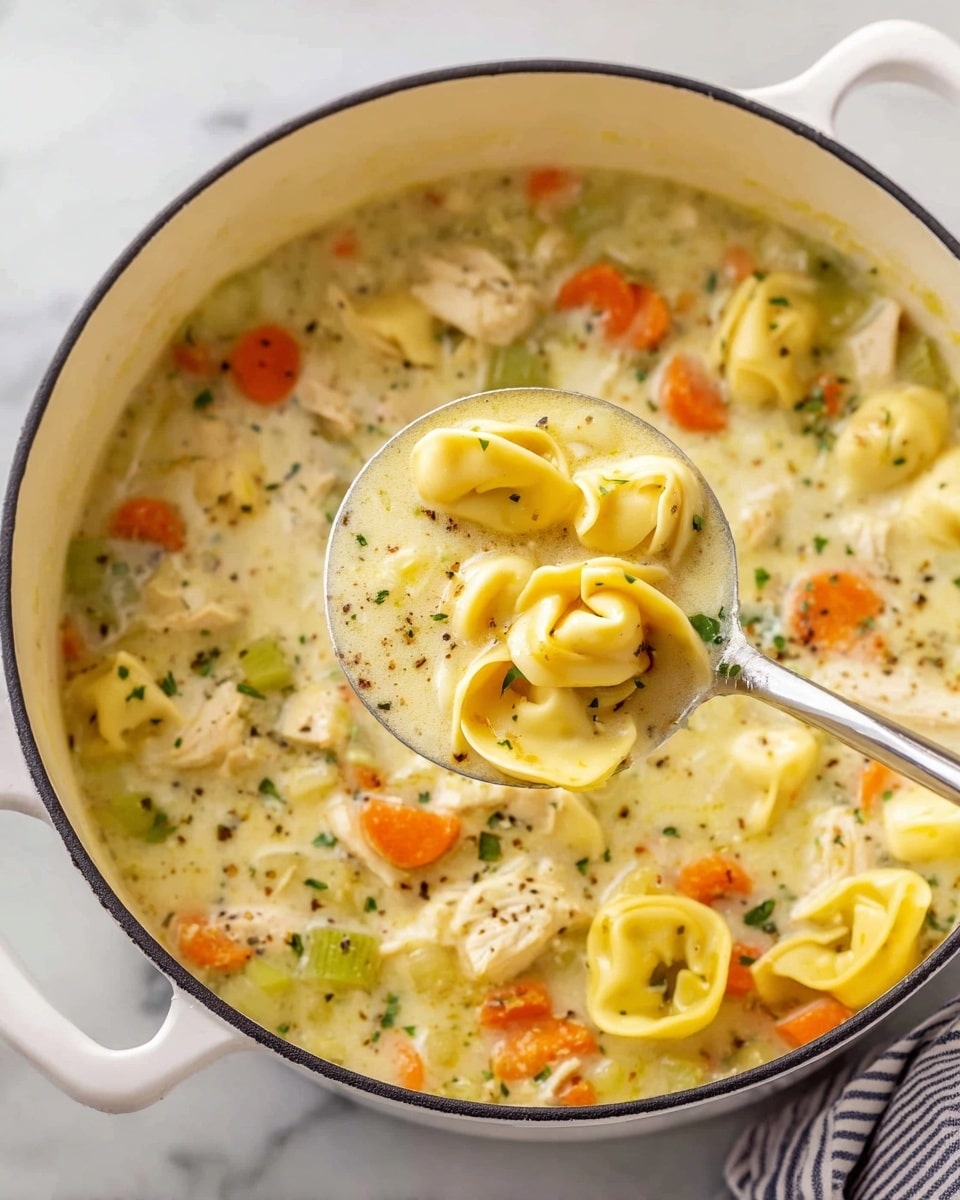 A white pot filled with creamy soup that has three main layers: the base layer is a thick, light yellow broth with specks of herbs throughout; the middle layer has chunks of orange carrots, green celery pieces, and small white bits of chicken; the top layer has yellow tortellini pasta floating on the surface. A silver ladle lifts some soup, showing a mix of the pasta, vegetables, and broth close up. The pot sits on a white marbled surface with a small part of a striped cloth visible in the corner. Photo taken with an iphone --ar 4:5 --v 7