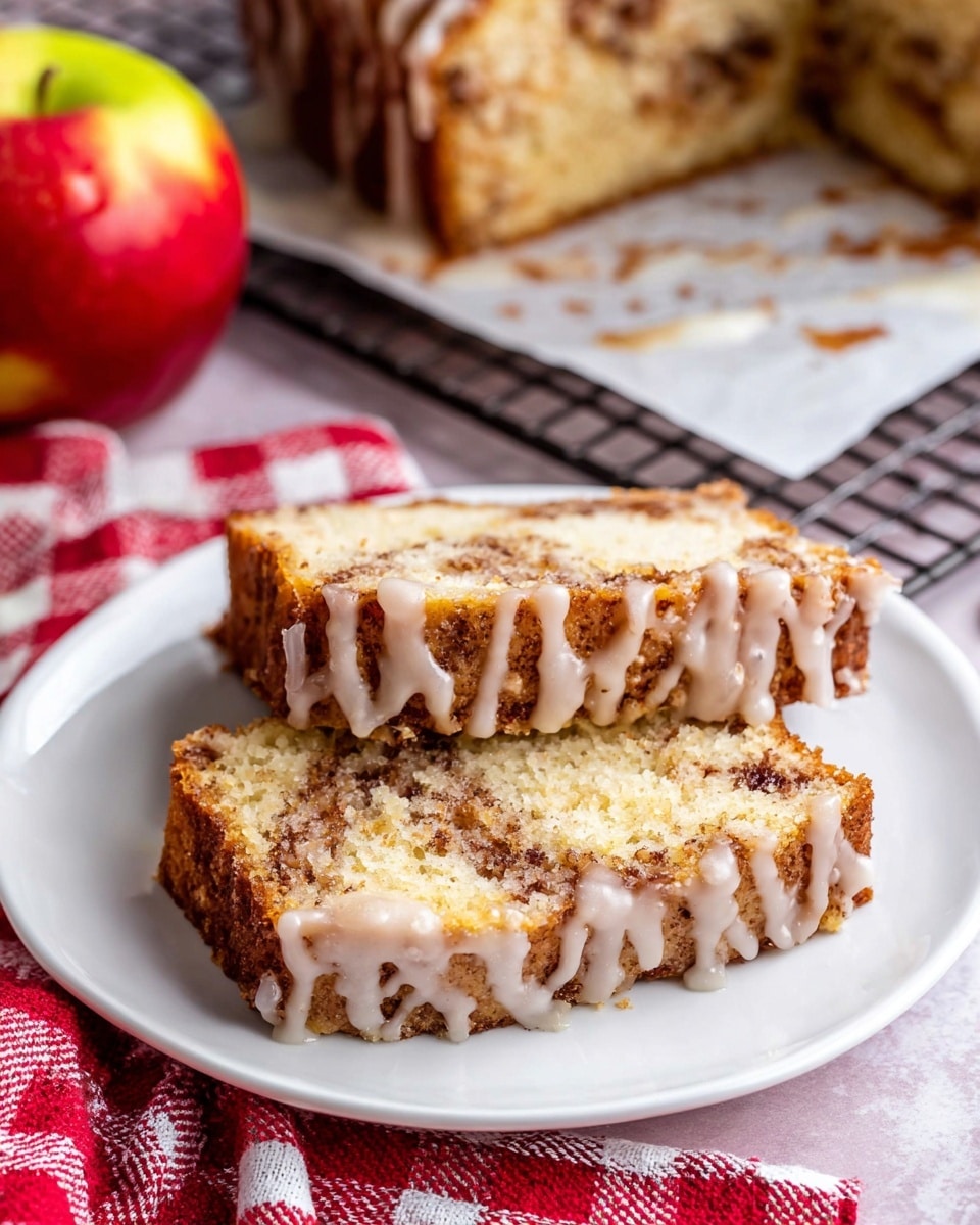 The image shows two slices of cake lying flat on a white plate. The cake has three layers: a light beige soft cake base with a visible texture, a middle brown cinnamon swirl layer that looks moist and filled with spices, and a white glaze drizzled unevenly over the entire top and edges, creating a shiny look. Behind the plate, there is a half apple with red and yellow skin resting on a white marbled surface. The background also shows more of the glaze-drizzled cake on white parchment paper on a baking rack. A red and white checkered cloth is partially seen under the plate. The photo was taken with an iphone --ar 4:5 --v 7