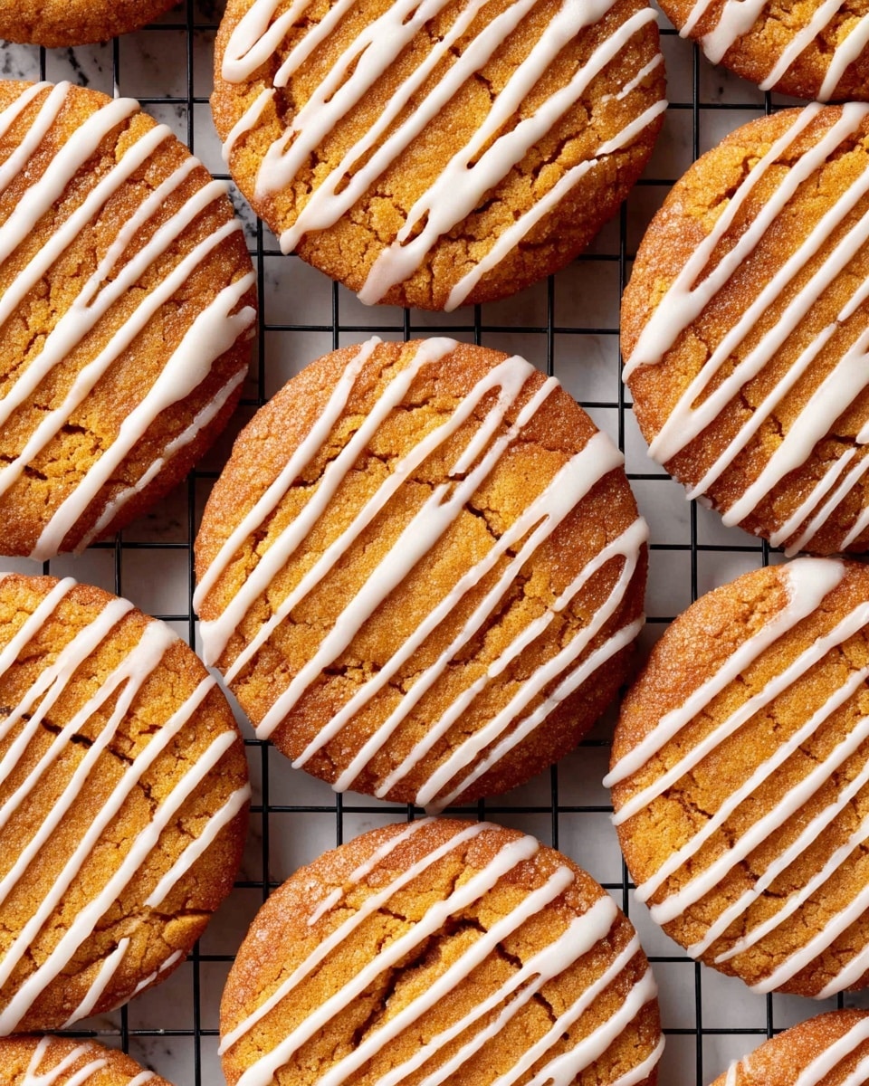 The image shows several round cookies placed on a cooling rack set against a white marbled texture background. Each cookie has a golden brown top layer with a slightly darker edge, showing a soft texture with small cracks on the surface. A white icing is drizzled evenly across each cookie in thin, straight diagonal lines, creating a contrasting pattern to the warm cookie colors. The cookies are closely arranged, filling most of the frame, and the grid of the cooling rack is visible beneath them. photo taken with an iphone --ar 4:5 --v 7