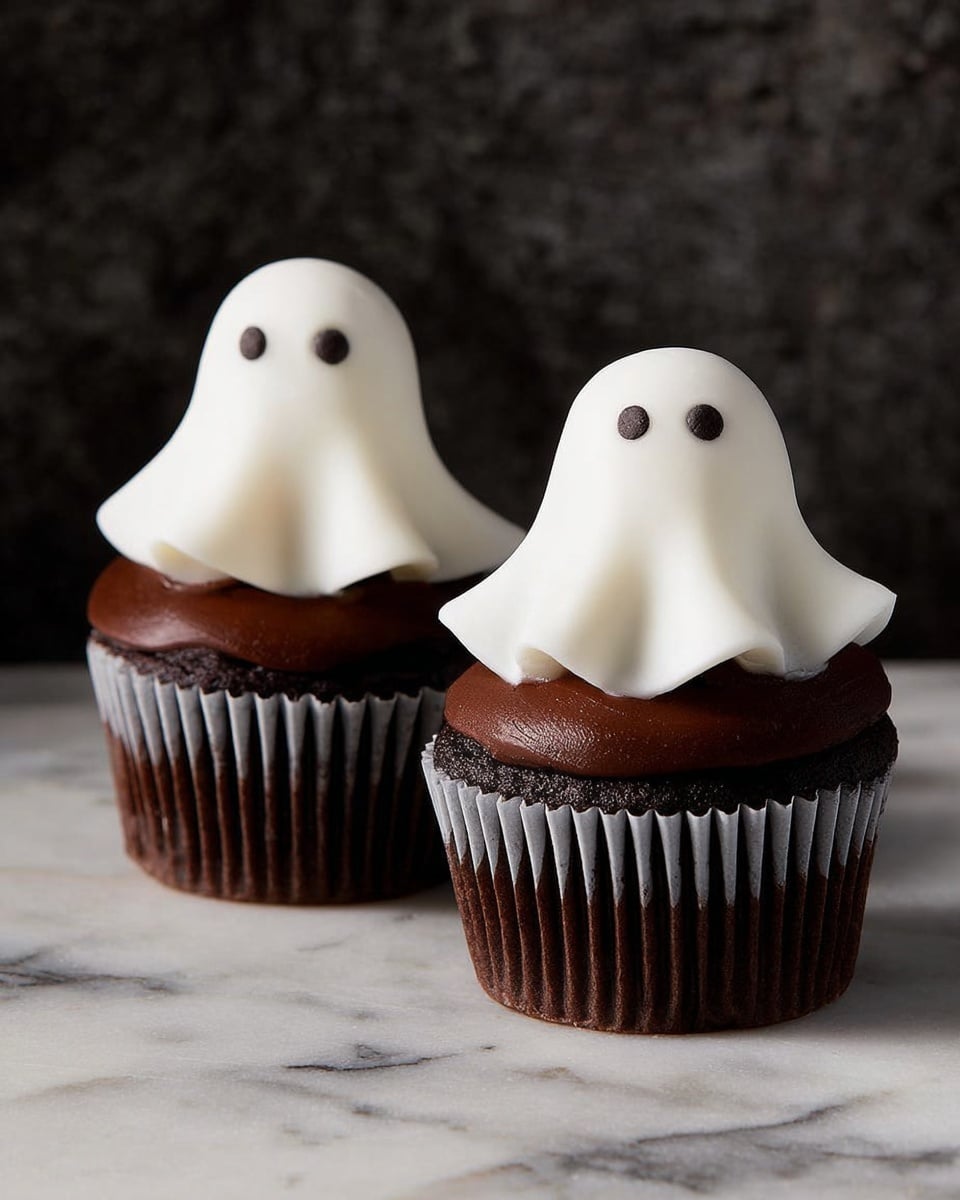 Two chocolate cupcakes sit side by side on a white marbled surface. Each cupcake has a dark brown cake base wrapped in a white paper liner. On top of the cake is a thick, smooth layer of shiny dark chocolate frosting. Covering the frosting is a white ghost shape made from soft fondant or icing, with two small round black dots for eyes. The ghosts have a draped, flowing look that gently hangs over the frosting edges. The background is dark and textured, making the cupcakes stand out clearly. photo taken with an iphone --ar 4:5 --v 7