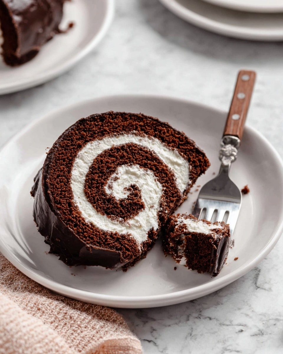 A single slice of chocolate roll cake is placed in the center of a white plate, showing the spiral layers clearly. The outer layer is dark and shiny chocolate, smooth and thick. Inside, alternating layers of dark chocolate sponge and fluffy white cream swirl tightly from the outer edge to the middle. A fork with a wooden handle rests on the plate holding a bite-sized piece of the cake. The background is a white marbled surface with parts of other white plates and a pale cloth visible around. photo taken with an iphone --ar 4:5 --v 7
