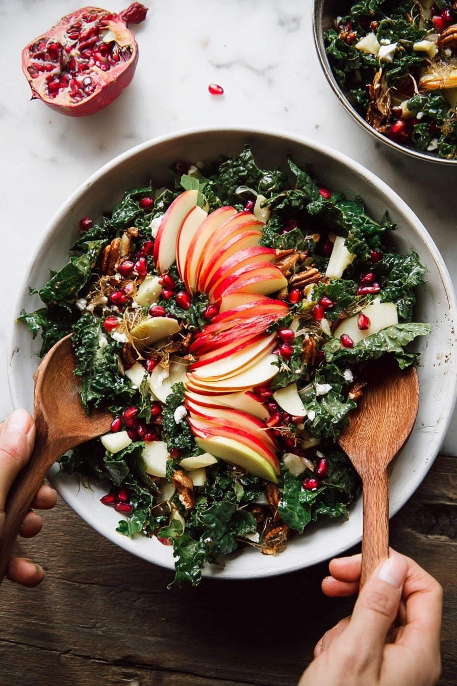 A white bowl filled with a fresh salad rests on a white marbled surface, showing layers of dark green chopped kale mixed with thin slices of red-skinned apple arranged in a fan shape on top. Bright red pomegranate seeds are scattered across the salad, adding spots of vibrant color. Golden brown toasted seeds and small bits of crispy brown topping are sprinkled on the salad for texture. Pieces of white cheese with a soft texture are visible beneath the kale. A woman's hand holds a wooden spoon on the bottom left while another woman's hand grips a second wooden spoon on the top right as they mix the salad. Photo taken with an iphone --ar 2:3 --v 7 - Fall Harvest Honeycrisp Apple and Kale Salad, autumn apple kale salad, healthy fall salad with prosciutto, seasonal kale and apple salad, pomegranate kale salad