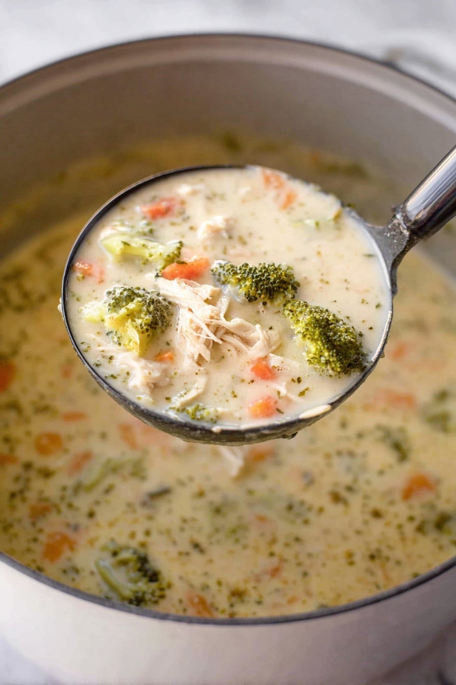 A close-up shot shows a ladle filled with creamy chicken and broccoli soup held above a pot. The soup has a thick, creamy texture with visible chunks of light beige shredded chicken, bright green broccoli florets, and small orange carrot pieces mixed throughout the light cream-colored broth. The surface beneath the pot is a white marbled texture. Photo taken with an iphone --ar 2:3 --v 7 - Creamy Chicken and Broccoli Soup, healthy chicken broccoli soup, easy creamy chicken soup, comforting chicken and broccoli dish, quick and nutritious soup