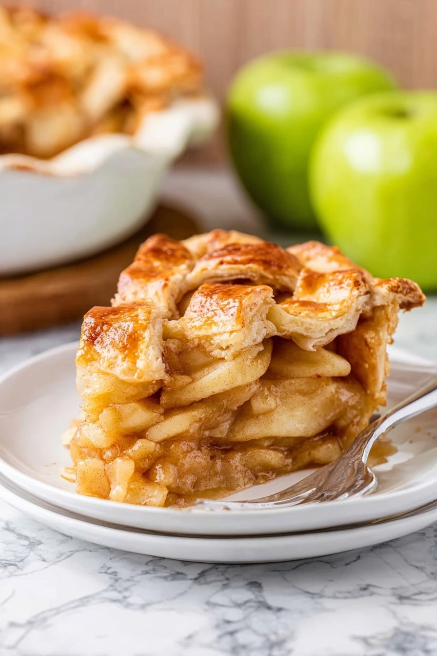 The image shows a slice of apple pie on a white plate with a silver fork on the side. The pie has a golden brown, flaky crust on top with a braided lattice pattern, and the edges are wavy and slightly crimped. Inside, there are roughly four layers of soft, cooked apple slices coated in a light brown cinnamon-spiced sauce. The filling looks tender and juicy, and you can see a little shine from the glaze. The background has a white marbled texture, and there are two green apples and a white ceramic dish with more pie behind the plate. photo taken with an iphone --ar 2:3 --v 7 - Apple Pie, best apple pie, homemade apple pie, classic apple pie, easy apple pie
