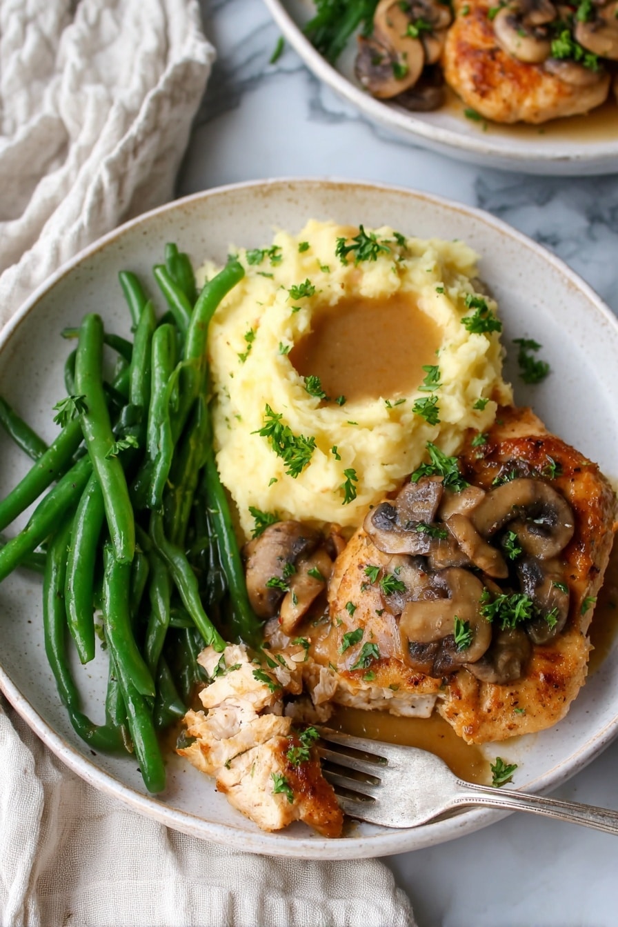 The image shows a white plate with three main parts: bright green cooked green beans placed on the left, a creamy mound of pale yellow mashed potatoes with a small pool of light brown gravy sitting on top in the upper right, and a golden brown cooked chicken piece covered with sliced sautéed mushrooms and chopped green parsley in the bottom right. A fork with a piece of chicken is resting on the edge of the plate, and the plate is set on a white marbled surface with a piece of off-white cloth nearby. Photo taken with an iphone --ar 2:3 --v 7 - Easy Chicken Marsala with Mushrooms, Chicken Marsala recipe, quick chicken Marsala, gourmet chicken dinner, mushroom chicken skillet