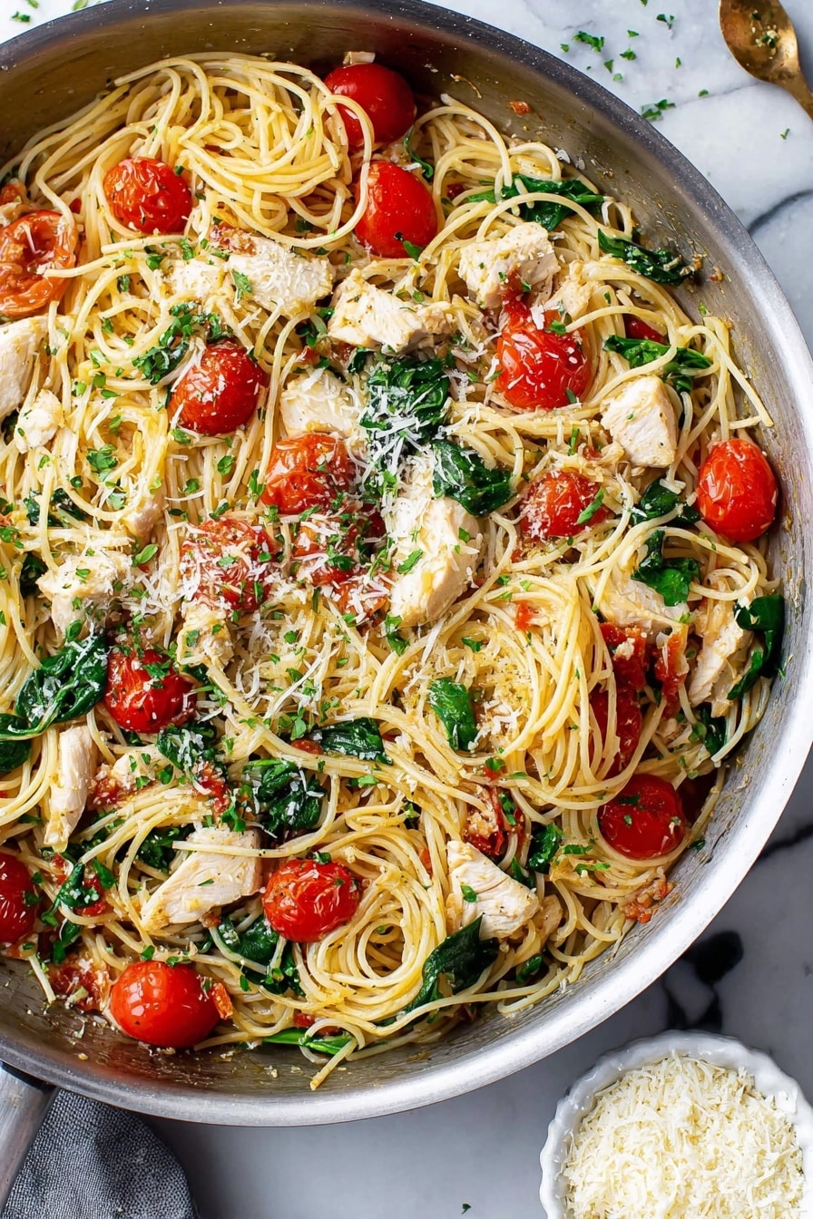 This image shows a pan filled with cooked thin spaghetti mixed with white chicken pieces, bright red cherry tomatoes cut in halves, and fresh green spinach leaves scattered throughout. The pasta looks soft and tangled, and there are small sprinkles of grated cheese and finely chopped green herbs on top. The pan sits on a white marbled surface, and near the bottom right corner, there is a small white bowl filled with more grated cheese. The whole dish looks fresh and colorful. photo taken with an iphone --ar 2:3 --v 7 - Creamy Lemon Garlic Chicken Scampi, lemon garlic chicken with spinach and cherry tomatoes, easy chicken and veggie pasta, quick lemon garlic chicken dinner, flavorful chicken scampi dish