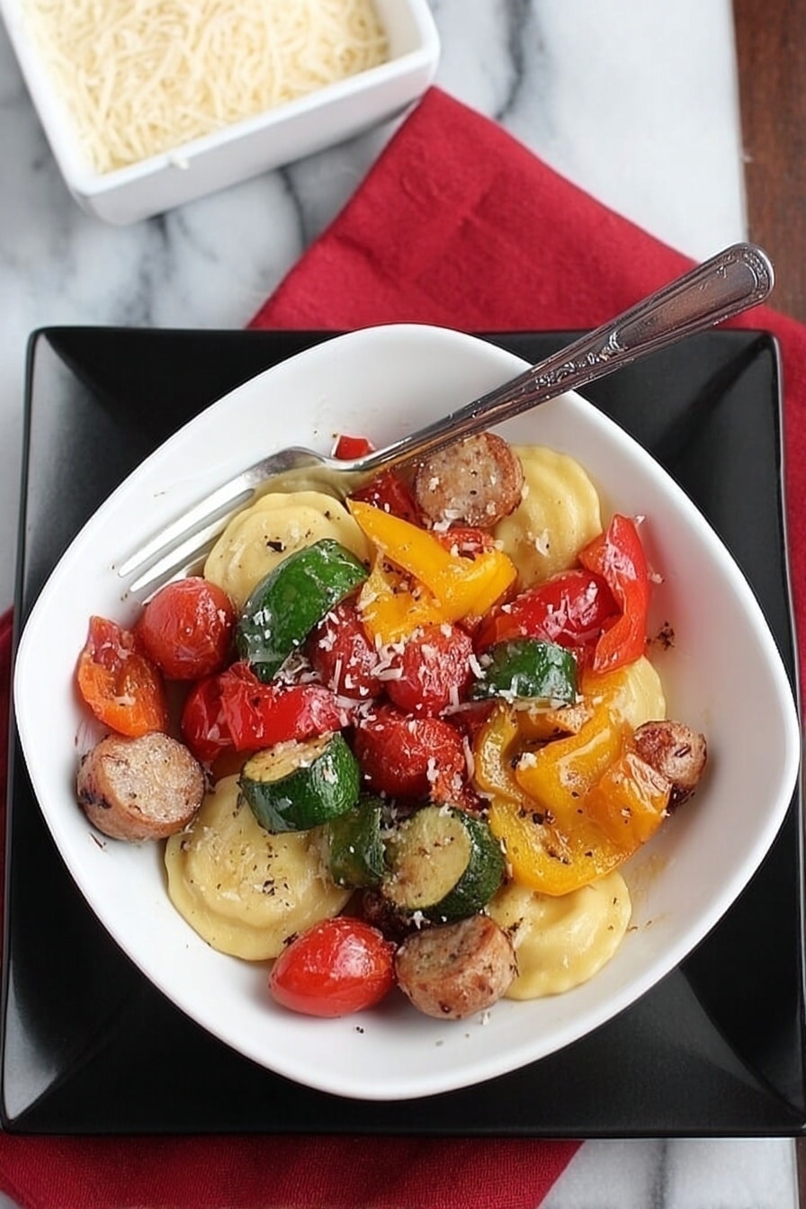 A white square bowl filled with a colorful mix of food sits on a larger black square plate, all placed on a white marbled surface with a red cloth napkin nearby. The bowl contains three round ravioli pieces at the bottom, light yellow in color with a smooth texture. On top of the ravioli are several pieces of sausage, sliced into thick rounds with a browned outer surface, along with large pieces of bell peppers in green, yellow, and red, each showing a slightly glossy and roasted texture. Scattered throughout are bright red cherry tomatoes, some whole, others split, and all glistening slightly. A silver fork rests inside the bowl, angled and leaning toward the right side. Nearby, a white square dish filled with grated cheese is partially visible. The photo taken with an iphone --ar 2:3 --v 7 - Lightning-Fast Cheesy Three-Pepper Ravioli with Italian Sausage, quick Italian sausage pasta, easy cheesy pepper ravioli, speedy pepper and sausage dinner, flavorful 20-minute pasta