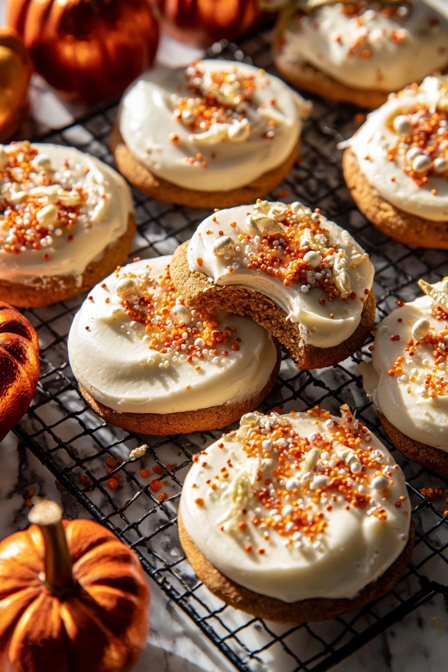 The image shows a group of round cookies, each with one thick, creamy white frosting layer on top. The frosting is smooth and spread evenly, decorated with small orange, white, and gold sprinkles scattered on the surface. One cookie is lifted slightly, showing the soft brown cookie base beneath the frosting. The cookies rest on a black wire cooling rack placed on a white marbled surface. Around the cookies, there are a few small, shiny dark orange mini pumpkins adding a warm autumn feel. Bright sunlight shines on the scene, creating strong shadows and highlighting the textures. Photo taken with an iphone --ar 2:3 --v 7 - Frosted Soft Pumpkin Sugar Cookies, pumpkin sugar cookie recipe, soft pumpkin cookies with cream cheese frosting, fall holiday pumpkin cookies, easy pumpkin cookie recipe