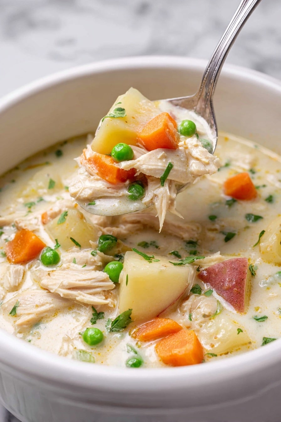 A white bowl filled with thick creamy chicken soup shows several layers: the base is a light cream broth, with chunks of light beige shredded chicken, bright orange carrot slices, small green peas, and white potato pieces with reddish skin. A silver spoon lifts a scoop of the soup, filled with all these colorful ingredients, positioned slightly above the bowl. The background is a white marbled texture, giving a clean and fresh look to the image. Photo taken with an iphone --ar 2:3 --v 7 - Slow Cooker Garlic Parmesan Chicken Stew, Healthy slow cooker chicken recipes, Comfort food chicken stew, Easy garlic parmesan chicken dish, Hearty slow cooker dinner