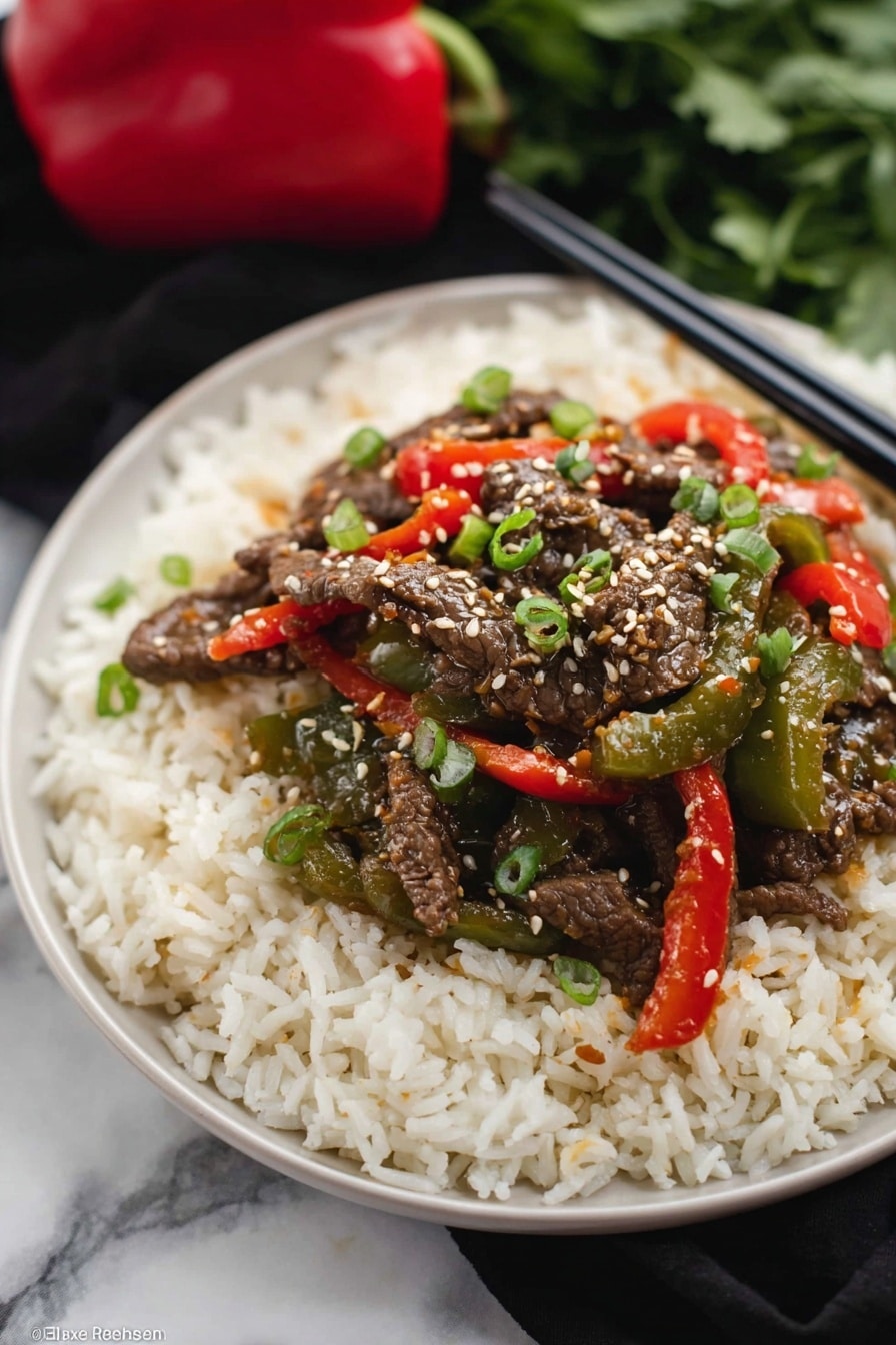 The dish shows three layers on a black plate: the bottom layer is a bed of fluffy white rice with a soft texture, the middle layer has bright green and red cooked bell peppers that look tender and shiny, and the top layer is dark brown strips of cooked beef covered with white sesame seeds and small pieces of green onion scattered on top. The background is a white marbled texture with a pair of dark chopsticks resting near the plate. photo taken with an iphone --ar 2:3 --v 7 - Crockpot Pepper Steak, slow cooker beef stir-fry, Easy Crockpot Beef Recipe, flavorful ground beef dinner, tender crockpot steak