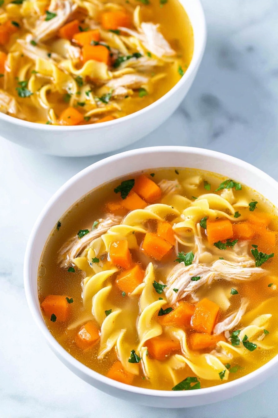 Two white bowls sit on a white marbled surface, each filled with a clear golden broth soup. Inside the soup are three main layers: bright orange carrot cubes scattered throughout, shredded pale pink chicken pieces, and yellow twisted egg noodles floating, mixed with small chopped green herbs and translucent onion bits. The colors mix well, creating a warm and fresh look. photo taken with an iphone --ar 2:3 --v 7 - Homemade Chicken Noodle Soup, chicken noodle soup recipe, comforting chicken soup, easy homemade chicken soup, cozy chicken noodle soup