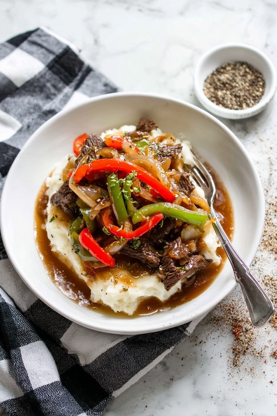 A white shallow bowl holds a layered dish with mashed potatoes at the bottom, creamy white and soft in texture. On top, there are strips of beef cooked dark brown, mixed with sautéed red and green bell pepper slices, and translucent cooked onions. The layers are covered with a glossy brown gravy that pools slightly at the base. A silver fork rests on the edge of the bowl. The bowl sits on a black and white checkered cloth, placed on a white marbled surface. To the top right, there is a small white dish with cracked black pepper scattered around it. photo taken with an iphone --ar 2:3 --v 7 - Pepper Steak with Onion, Pepper Steak with Onion recipe, Easy Pepper Steak with Onion, Tender Pepper Steak with Onion, Beef and Onion Stir Fry