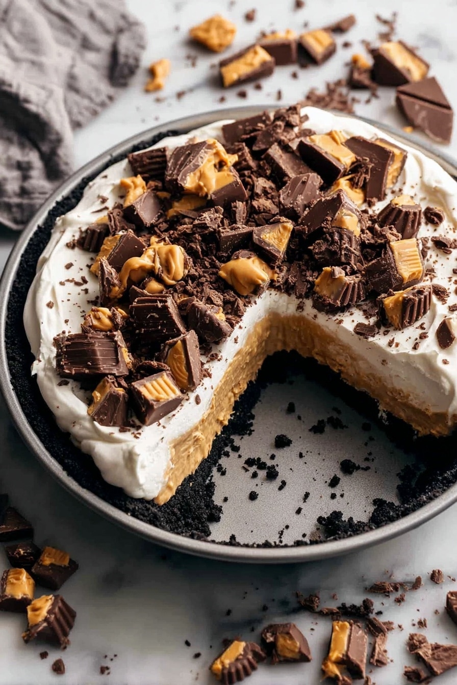 A round dessert in a gray pan has three layers: a dark crumbled base, a thick light brown peanut butter layer, and a smooth white cream layer on top. The cream is covered with many pieces of dark chocolate and peanut butter candy scattered unevenly. The pan is placed on a white marbled surface with more pieces of the same chocolate candy spread around it. A large wedge is missing from the dessert, showing the three colorful layers clearly. photo taken with an iphone --ar 2:3 --v 7 - Chocolate Peanut Butter Pie, Chocolate Peanut Butter Pie Recipe, Easy Peanut Butter Pie, No-Bake Chocolate Pie, Instant Peanut Butter Dessert