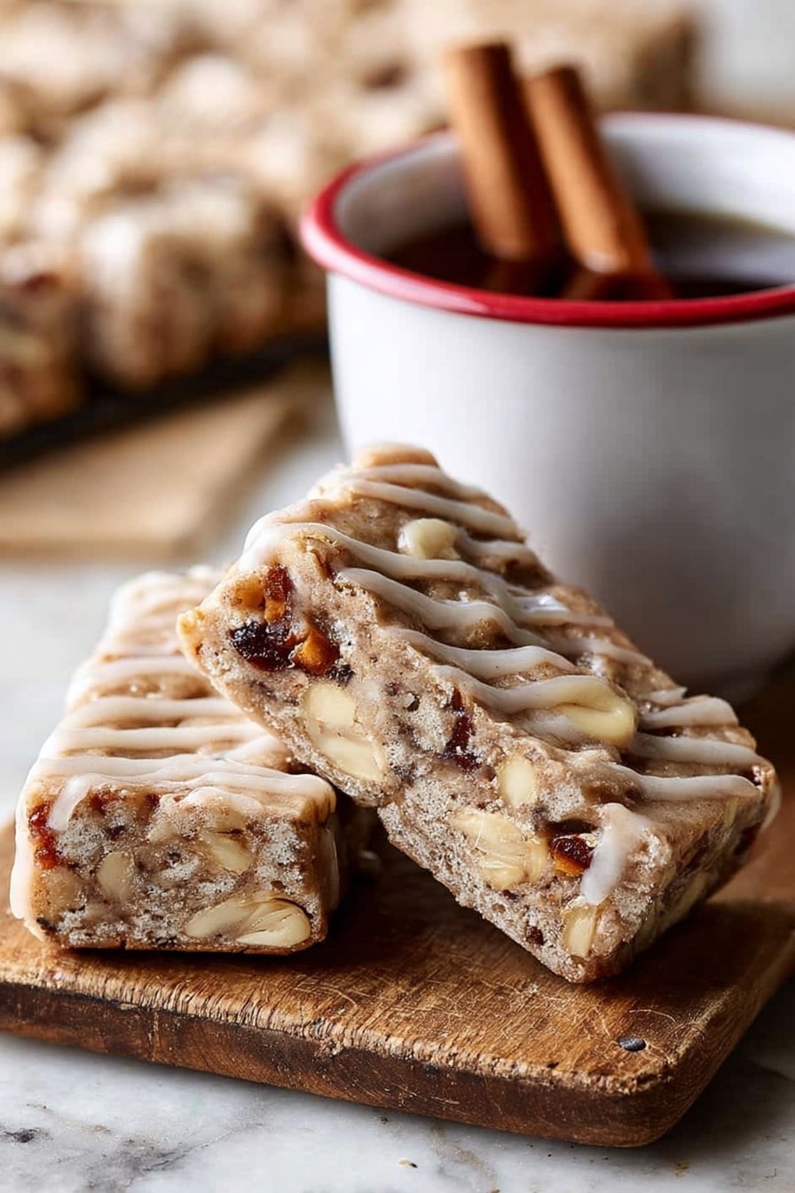 The image shows two triangular bars leaning against each other on a wooden board with a cinnamon stick nearby. Each bar has a thick, light brown base with a slightly crumbly texture, filled with visible chunks of nuts and possibly dried fruit, giving darker brown and creamy white spots inside. The bars are drizzled with a light tan glaze in thin lines across the top and sides. Next to the bars is a white cup with a red rim containing a dark liquid and two cinnamon sticks inside. The background is blurred but shows more bars on a white marbled surface. photo taken with an iphone --ar 2:3 --v 7 - Brown Butter Apple Blondies with Cinnamon Maple Glaze, fall apple blondies, cozy dessert recipes, cinnamon glazed blondies, easy apple dessert