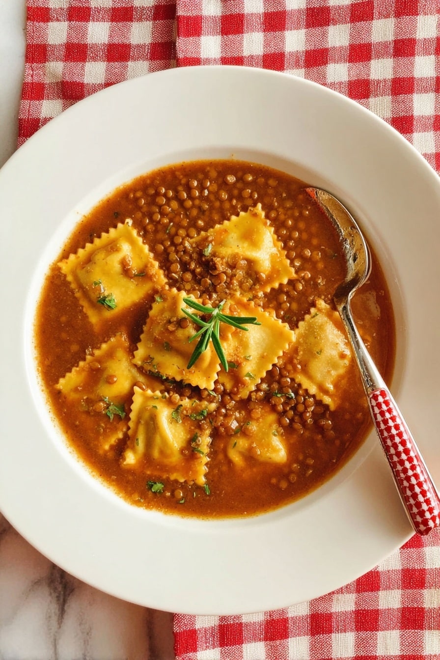 A shallow white plate sits on a red and white checkered cloth over a white marbled surface, filled with a brown lentil soup base. The soup contains square yellow ravioli pieces with ruffled edges layered throughout, and a small green sprig of rosemary rests on top in the middle. A silver spoon with a red and white patterned handle is placed inside the soup on the right side of the plate. Photo taken with an iphone --ar 2:3 --v 7 - Umbrian Lentil Soup with Pasta, Umbrian Lentil Soup, Italian Lentil Soup, hearty lentil and pasta soup, traditional Italian lentil dish