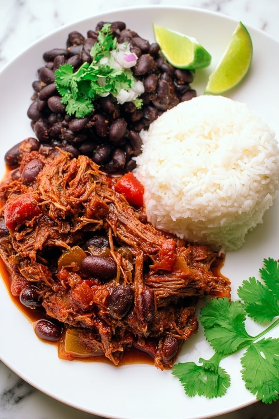 A white plate with three main layers: on the top right, a mound of white fluffy rice with a soft texture; on the top left, a scoop of cooked black beans mixed with small onion pieces, topped with a sprig of fresh green cilantro; and covering the bottom half of the plate, a rich, thick reddish-brown stew with shredded meat and chunks of vegetables like olives and red peppers. On the right edge of the plate, a lime wedge adds a touch of bright green. Fresh cilantro leaves lie on the white marbled surface near the plate. Photo taken with an iphone --ar 2:3 --v 7 - Slow Cooker Ropa Vieja, Cuban shredded beef stew, easy Cuban recipes, beef stew in slow cooker, authentic Cuban dishes