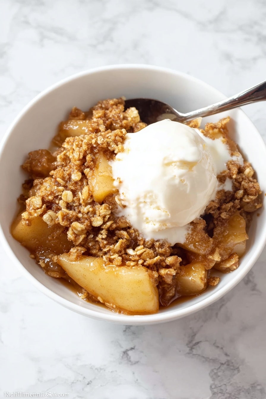 A close-up view of a white bowl filled with a warm apple dessert that has three main layers: a soft layer of sliced cooked apples with a light golden color on the bottom and middle, covered by a thick, sticky caramel sauce that gives a shiny, wet look, and topped with a crumbly, brown oat topping that looks crunchy with small clusters scattered unevenly on top. The dish looks moist and inviting, with the caramel sauce slightly dripping between the apple slices and crumbs. The white bowl sits against a white marbled surface. Photo taken with an iphone --ar 2:3 --v 7 - Healthy Apple Crisp with Oat Pecan Topping, healthy apple crisp recipes, nutritious apple crisp dessert, wholesome apple crisp dessert, easy healthy apple crisp