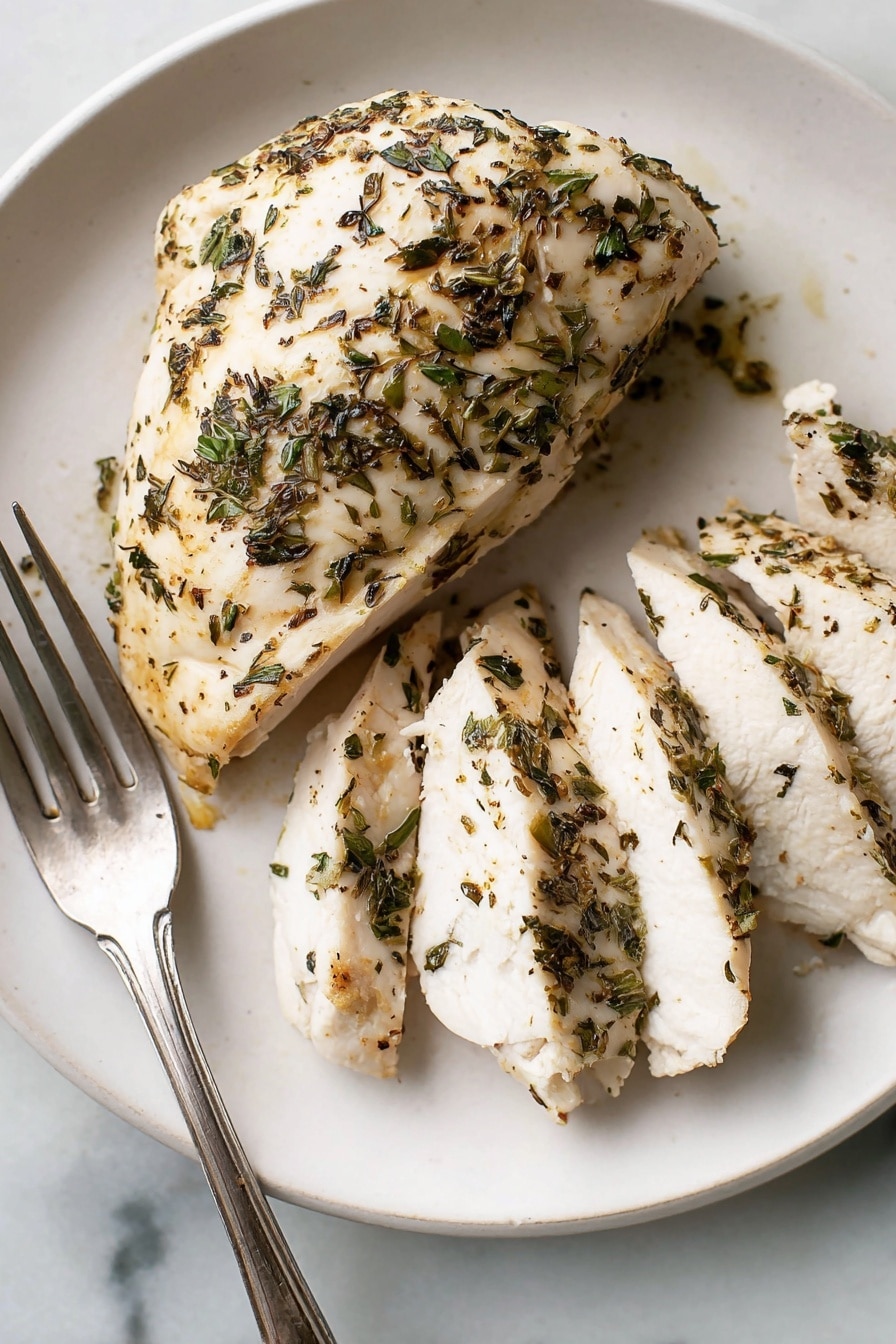 Two cooked chicken breasts with a light golden color are placed side by side in a white square baking dish. The chicken is sprinkled with small bits of dark green and brown herbs that cover the top surface of each piece. Some orange-brown spots of cooked juices and herbs stick lightly to the bottom and sides of the dish. A pair of silver tongs rests near the top right corner of the dish on a white marbled surface. The overall setting has a clean, simple look with soft lighting. photo taken with an iphone --ar 2:3 --v 7 - Herb Baked Chicken Breast, quick healthy chicken dinner, easy baked chicken recipes, juicy baked chicken breast, flavorful chicken breast
