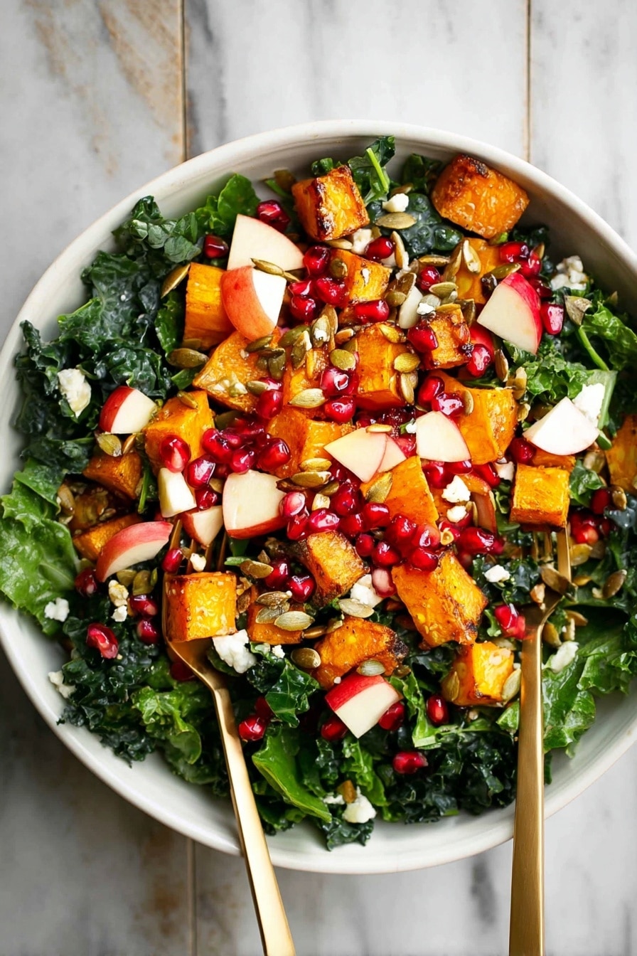 A white bowl filled with a colorful salad sits on a white marbled surface. The salad has three main layers: at the bottom, there are dark green kale leaves, fresh and leafy. On top of the kale, there are medium-sized orange roasted cubes of squash scattered around. Mixed in with these are small pieces of red apple with white inside, bright red pomegranate seeds, and some white small chunks of cheese. The salad is finished with some brown pumpkin seeds sprinkled evenly. Two metallic gold forks are placed inside the bowl, one on each side. Photo taken with an iphone --ar 2:3 --v 7 - Fall Roasted Butternut Squash Salad, roasted butternut squash salad, seasonal fall salad, healthy roasted vegetable salad, easy autumn salad