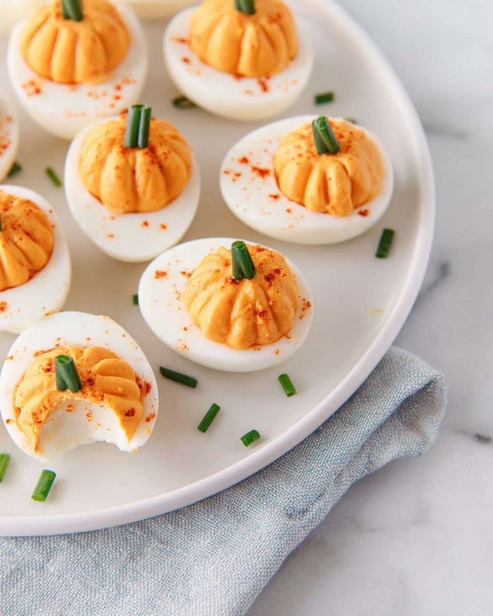 The image shows several deviled eggs on a white marbled surface, each egg half with a smooth white outer layer and filled with a creamy orange filling. The filling is shaped with ridges to look like a pumpkin, topped with a small green chive piece that stands upright as a stem. There is a light sprinkle of red paprika powder on the orange filling, adding texture and color contrast. The eggs are arranged neatly, filling the frame evenly with no other visible items. photo taken with an iphone --ar 4:5 --v 7