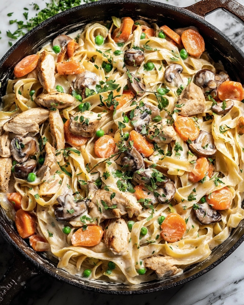 A black cast iron pan filled with creamy fettuccine pasta mixed with sliced mushrooms, thinly sliced pieces of white meat, orange round carrot slices, and small green peas, all coated in a light creamy sauce and sprinkled with green chopped parsley on top. The pan rests on a white marbled surface with two lemon halves nearby and a fork placed inside the pan on the right side. Photo taken with an iphone --ar 4:5 --v 7