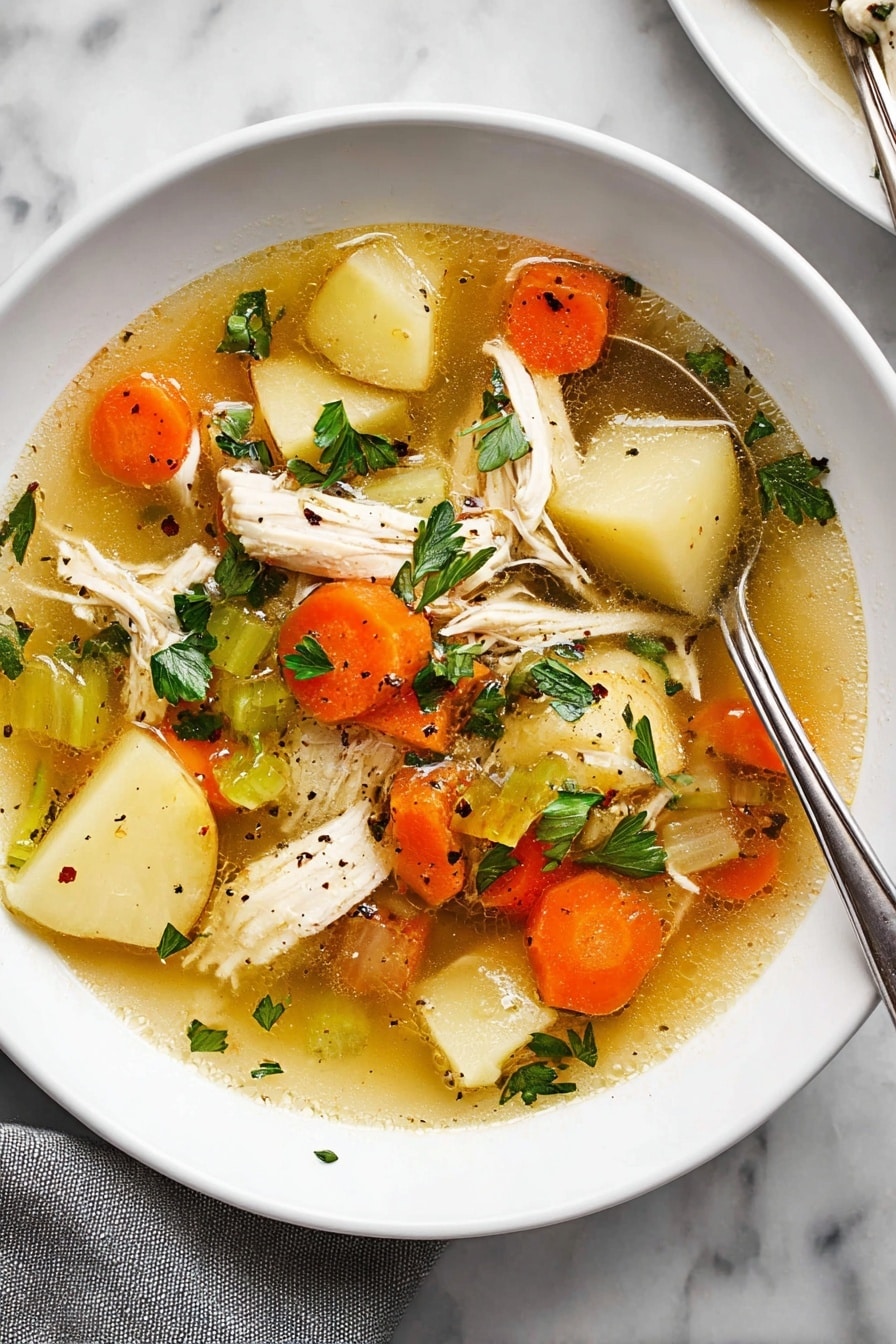 The image shows a white plate filled with clear chicken soup that has a golden broth base. Inside the soup, there are several layers: large pieces of white shredded chicken, sliced orange carrots, light beige potato slices, and sections of green celery. Scattered on top are fresh green parsley leaves and small black pepper bits. A silver spoon is partially dipped into the soup on the right side of the plate, resting against the edge. The plate is placed on a white marbled surface, with a grey cloth partially visible at the bottom left corner. photo taken with an iphone --ar 2:3 --v 7 - Ultimate Chicken Soup, chicken soup recipe, cozy chicken soup, homemade chicken soup, healthy chicken soup