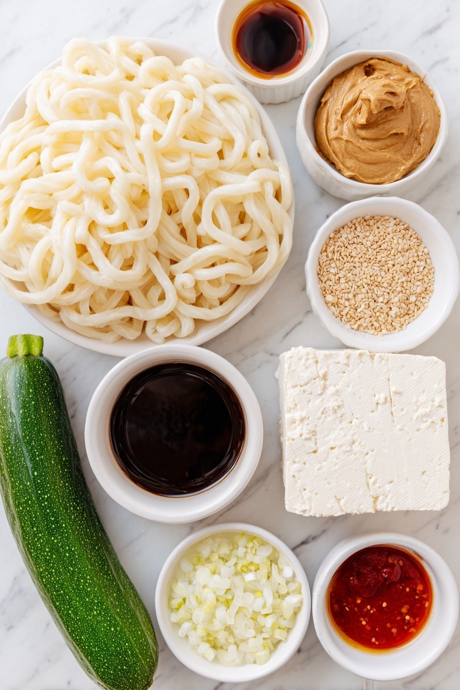 Flat lay of thick cut udon noodles arranged loosely, a whole fresh cucumber with glossy dark green skin, a block of extra firm tofu with a smooth creamy white surface, a small bunch of vibrant green scallions, a small mound of shiny light brown sesame seeds, a small white ceramic bowl of creamy peanut butter, a small white ceramic bowl filled with dark soy sauce, a small white ceramic bowl containing golden toasted sesame oil, a small white ceramic bowl with bright red sriracha, a small white ceramic bowl holding clear rice vinegar, a small white ceramic bowl with finely minced or powdered garlic, a small white ceramic bowl with finely minced or powdered ginger, a small white ceramic bowl of steaming hot water, all placed on a clean white marble surface, soft natural light, photo taken with an iPhone, professional food photography style, fresh ingredients, white ceramic bowls, no bottles, no duplicates, no utensils, no packaging --ar 2:3 --v 7 --p m7354615311229779997 - Easy Peanut Udon Noodles, peanut udon noodles, quick udon recipes, Asian noodle dishes, flavorful udon stir-fry