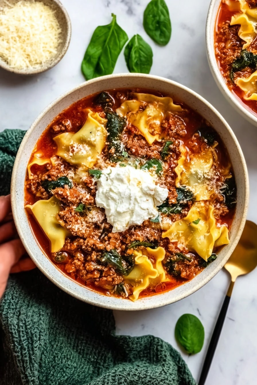 The image shows a round bowl filled with three main layers: the base layer is wide, flat, curly-edged lasagna noodles in a light tan color, partially submerged in red tomato sauce; the middle layer is a thick spread of cooked ground meat, dark brown and crumbly, mixed with bright green spinach leaves; the top layer features melted white cheese blobs scattered unevenly over the meat and sauce. Next to the bowl, on a white marbled surface, there is a small black bowl filled with finely grated pale yellow cheese, a sprig of fresh spinach nearby, and gold-colored fork and spoon resting on a textured cloth. The photo taken with an iphone --ar 2:3 --v 7 - One Pot Lasagna Soup, easy lasagna soup recipe, quick dinner ideas, hearty soup recipes, one pot pasta recipes