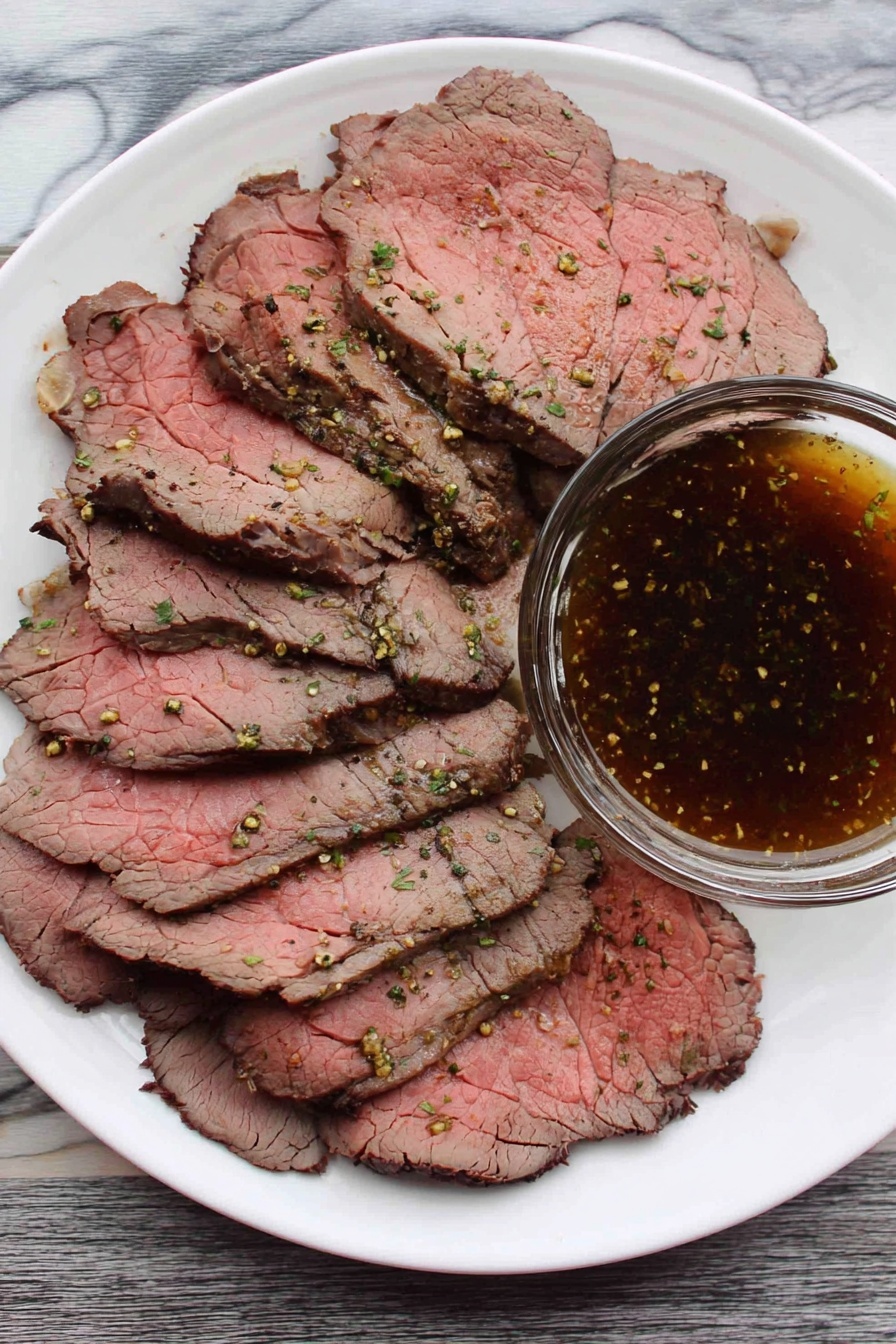 A white plate filled with several thin slices of roast beef, showing pink centers and darker brown edges with visible seasoning and small green herb bits. On the side of the plate, there is a clear glass bowl filled with a dark brown, speckled dipping sauce. The plate is placed on a white marbled surface. photo taken with an iphone --ar 2:3 --v 7 - Easy Roast Beef Top Round, tender roast beef recipe, simple beef roast, beginner-friendly roast beef, juicy top round roast