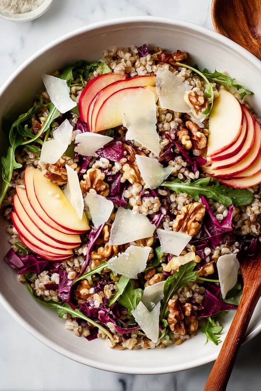 A white bowl filled with a colorful salad sitting on a white marbled surface. The salad has several layers: at the base there are light brown grains spread evenly, mixed with thin dark purple-red cabbage strips and bright green arugula leaves scattered throughout. On top of this are thin slices of red apple with white inside, placed around the bowl. There are also chunks of light brown walnuts spread across, and thin, uneven white cheese shavings scattered over everything. A wooden spoon is partly visible on the right side of the bowl. photo taken with an iphone --ar 2:3 --v 7 - Nutty Farro Salad with Apples and Arugula, healthy farro salad recipes, fruit and nut salad ideas, easy vegetarian salads, flavorful grain salads