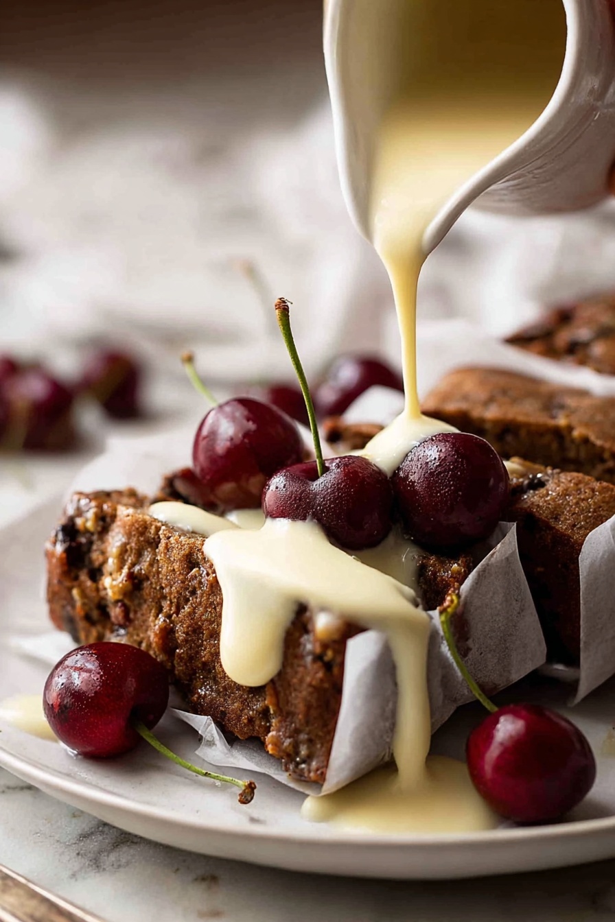 A white plate holds a dark brown cake with a rough texture, sliced into pieces and wrapped in white paper secured with small pins. The cake is topped with several shiny, deep red cherries with green stems. A creamy pale yellow sauce is being poured over the cake from a white pitcher, covering parts of the cake and dripping onto the plate. The white marbled surface beneath contrasts softly with the rich colors of the cake and cherries. Woman's hand is holding the pitcher. Photo taken with an iphone --ar 2:3 --v 7 - Easy Moist Christmas Fruit Cake, Christmas fruit cake recipe, holiday fruit cake, moist festive cake, simple holiday dessert