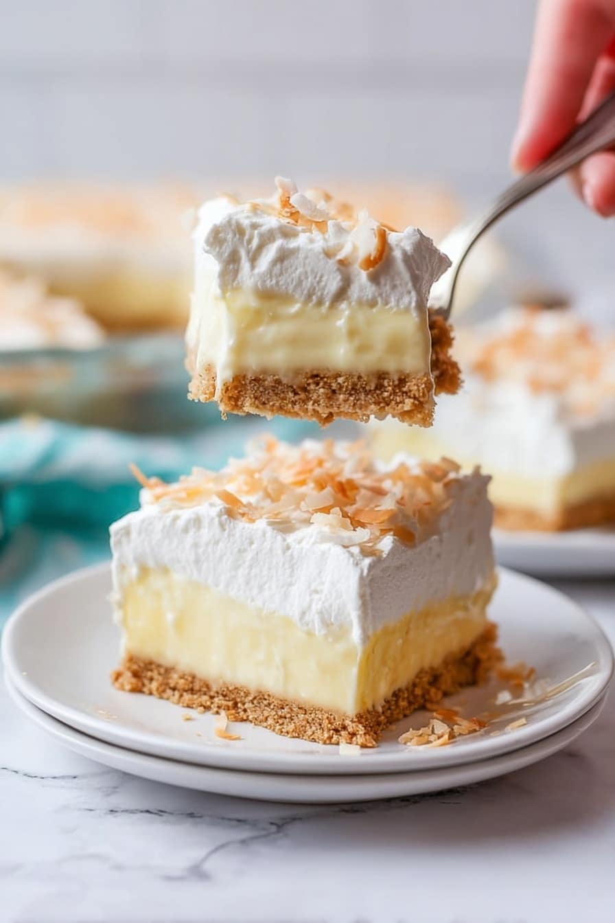The image shows a slice of a three-layer creamy dessert on a white plate set on a white marbled surface. The bottom layer is a crumbly light brown crust. The middle layer is thick and pale yellow with a smooth texture like pudding. The top layer is white and fluffy, appearing like whipped cream, sprinkled lightly with small toasted shreds that look like coconut. A woman's hand holds a fork above the plate, lifting a piece of the dessert that clearly shows all three layers in a close-up view. The background is softly blurred, with more slices of the dessert visible. photo taken with an iphone --ar 2:3 --v 7 - Coconut Cream Pie, Coconut Cream Pie Recipe, Best Coconut Pie, Easy Coconut Cream Pie, Creamy Coconut Dessert