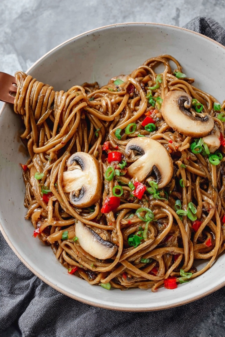 A white bowl is filled with thick noodles coated in a glossy brown sauce, mixed with small pieces of red bell pepper and garnished with finely chopped green onions. On top, there are three large slices of light brown mushrooms with darker edges, laid out neatly. A copper fork is twirling some noodles on the lower left side of the bowl. The bowl sits on a soft grey cloth on a white marbled surface. photo taken with an iphone --ar 2:3 --v 7 - Vegan Kung Pao Pasta, vegan pasta recipes, plant-based Asian pasta, spicy vegan pasta dish, easy vegan dinner ideas
