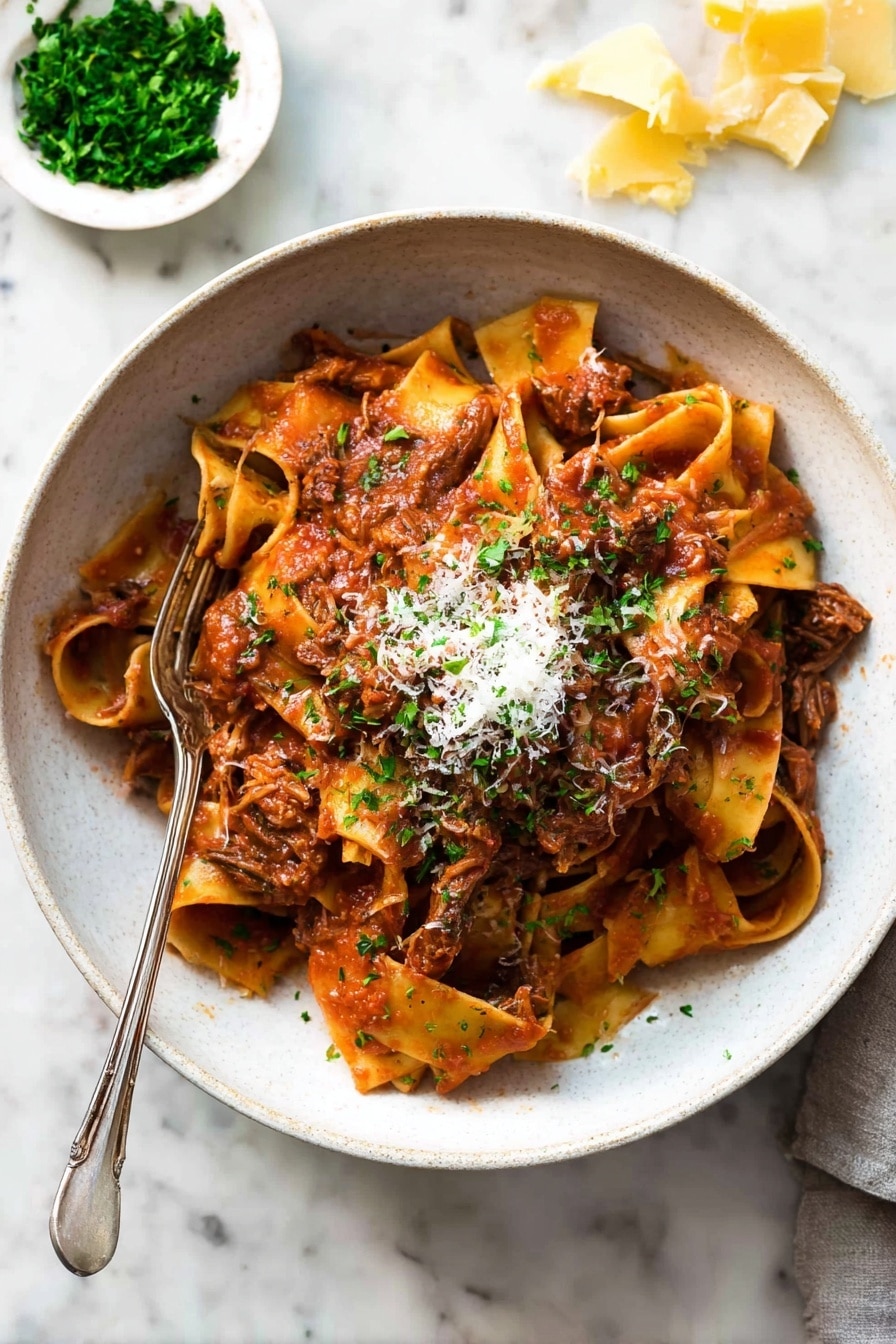 A bowl filled with wide, soft pasta noodles layered with shredded brown meat mixed in a thick red tomato sauce. The pasta sits in a white bowl, topped with a small pile of grated light cheese and finely chopped green herbs. A fork is placed inside the bowl, resting on the pasta. The background shows a white marbled surface with a small white dish holding chopped green herbs and pieces of yellow cheese scattered nearby. Photo taken with an iphone --ar 2:3 --v 7 - Slow Cooked Beef Ragu with Pasta, Italian Beef Ragu, Easy Beef Ragu Recipe, Comforting Pasta Dish, Slow Cooker Beef Pasta