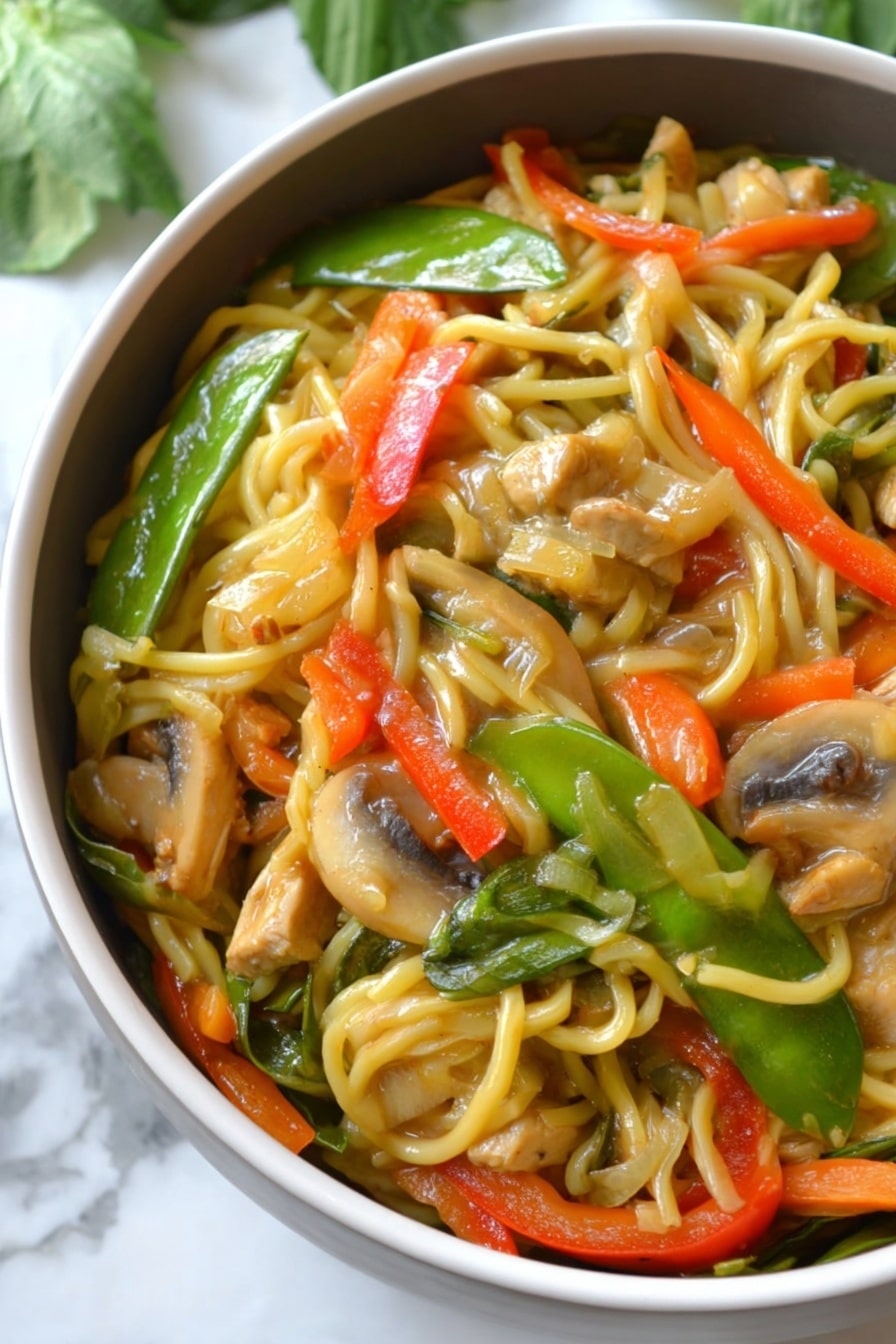 The image shows a close-up of a bowl filled with a colorful noodle stir-fry. The bottom layer consists of long, light yellow noodles, mixed evenly with sliced vegetables including bright green snow peas, orange thin carrot strips, chunky red bell pepper pieces, and light brown mushroom slices. There are also pieces of light tan tofu or chicken mixed into the dish. The noodles and vegetables are coated with a glossy sauce, giving them a shiny and slightly wet texture. The bowl is white, and it sits on a white marbled surface with some green leaves blurred in the background. photo taken with an iphone --ar 2:3 --v 7 - Instant Pot Chicken Lo Mein, easy chicken lo mein, healthy chicken noodle stir-fry, quick weeknight dinner recipes, one-pot lo mein