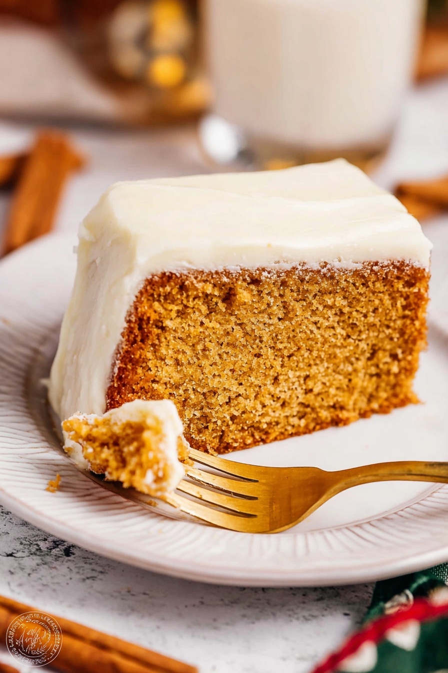 The image shows a slice of thick, light brown cake with a moist texture, topped with a thick white frosting layer covering the top and sides. The slice is placed on a white plate with a subtle embossed design along the edge. A golden fork is cutting into the cake slice. The background has a white marbled texture with blurred elements including cinnamon sticks and a glass cup. Warm lighting highlights the soft texture of the frosting and the crumb of the cake. Photo taken with an iphone --ar 2:3 --v 7 - Eggnog Bread with Spiced Glaze, festive eggnog bread, holiday bread recipes, easy eggnog bread, spiced holiday baked goods