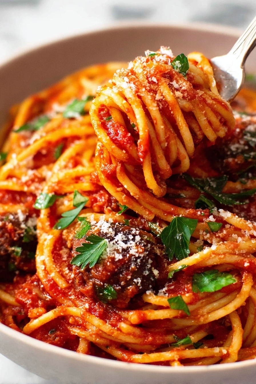 The image shows a close-up of a white bowl full of spaghetti pasta covered in bright red tomato sauce. The spaghetti strands are twisted around a silver fork that is lifting some noodles from the bowl, with a piece of dark brown meatball also on the fork. The pasta is sprinkled with white grated cheese and small green parsley leaves scattered on top, adding a fresh color touch. The background surface is a white marble texture, softly blurred to keep focus on the vibrant pasta dish. Photo taken with an iphone --ar 2:3 --v 7 - Eggplant Pasta alla Norma, Eggplant pasta recipe, Sicilian pasta dishes, Roasted eggplant pasta, Vegetarian pasta recipes