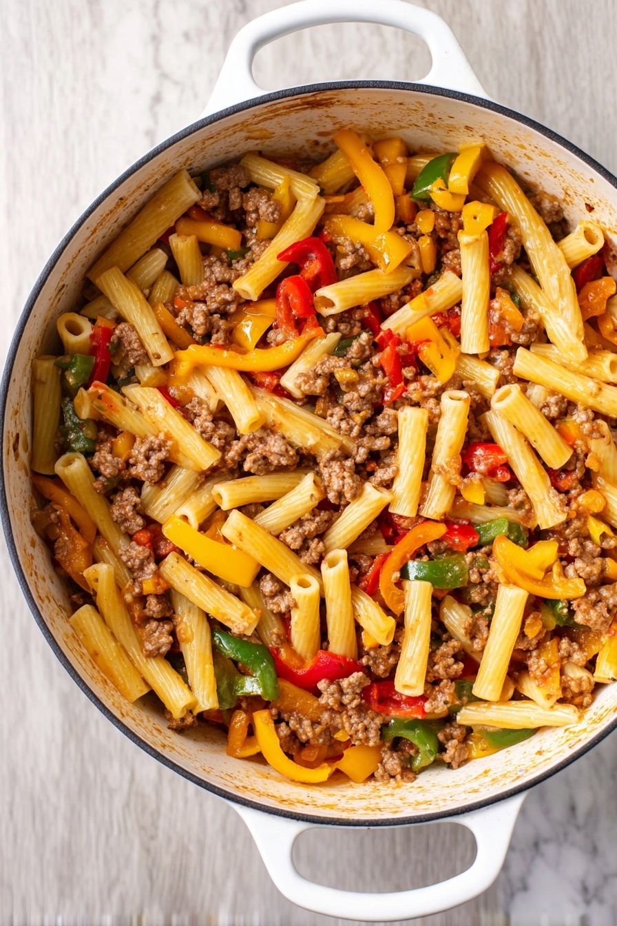 This image shows a white pot filled with a pasta dish featuring about three layers of ingredients. The bottom layer is short, tube-shaped pasta in a light yellow color. On top of this, there are chunks of cooked ground meat scattered throughout, appearing brown and crumbly. The top layer is mixed vegetables, including strips of red, yellow, and green bell peppers, adding bright colors and a fresh texture. The pot has white handles and sits on a white marbled surface. Photo taken with an iphone --ar 2:3 --v 7 - Italian Sausage and Peppers Pasta, Italian Sausage and Peppers Pasta Recipe, easy Italian sausage pasta, quick sausage and pepper pasta, flavorful sausage pasta dish