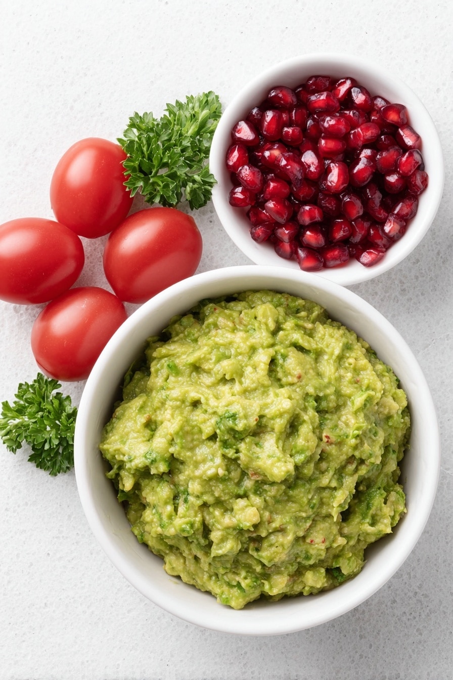 Flat lay of a simple white ceramic bowl filled with fresh green guacamole, a small white bowl containing bright red pomegranate seeds, a cluster of ripe red cherry tomatoes, and a few vibrant green sprigs of parsley placed neatly around the bowls, all arranged with perfect symmetry and balanced proportions, placed on a clean white marble surface, soft natural light, photo taken with an iPhone, professional food photography style, fresh ingredients, white ceramic bowls, no bottles, no duplicates, no utensils, no packaging --ar 2:3 --v 7 --p m7354615311229779997 - Festive Guacamole with Pomegranate & Tomatoes, holiday guacamole, colorful party dip, easy holiday appetizer, quick festive salsa