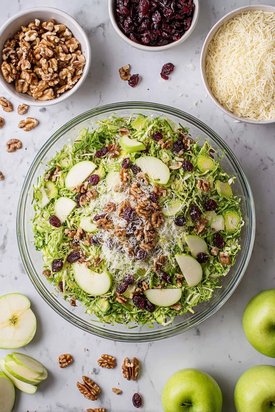 A large clear glass bowl filled with a fresh salad showing three layers: the bottom layer is shredded green Brussels sprouts, the middle layer is thinly sliced green apple slices placed evenly around, and the top layer is scattered walnut pieces, dark red dried cranberries, and small white grated cheese bits, all on a white marbled surface. Around the bowl are small white bowls containing walnuts, grated cheese, and dried cranberries, along with whole and sliced green apples and loose salad leaves scattered nearby. Photo taken with an iphone --ar 2:3 --v 7 - Brussels Sprouts Apple Cranberry Salad, healthy holiday salad, easy Brussels sprouts salad, fall veggie salad with cranberries, quick festive salad