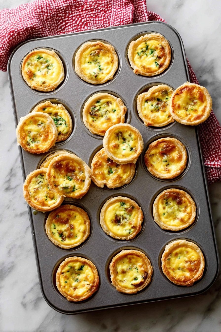 A gray metal muffin tray filled with 24 mini egg tarts, each tart consisting of a golden brown crust that forms a cup holding a smooth, creamy yellow egg filling mixed with small green and brown bits of vegetables or meat. Some tarts are slightly raised above the tray’s edge, showing a crisp outer layer, while a few are tilted or removed, revealing their round, flaky textured bottoms. The tray rests on a white marbled surface with a red and white checkered towel partly visible at the top left corner. Photo taken with an iphone --ar 2:3 --v 7 - Mini Quiche with Flaky Pie Crust, mini quiche recipes, easy quiche ideas, brunch party recipes, savory snack bites