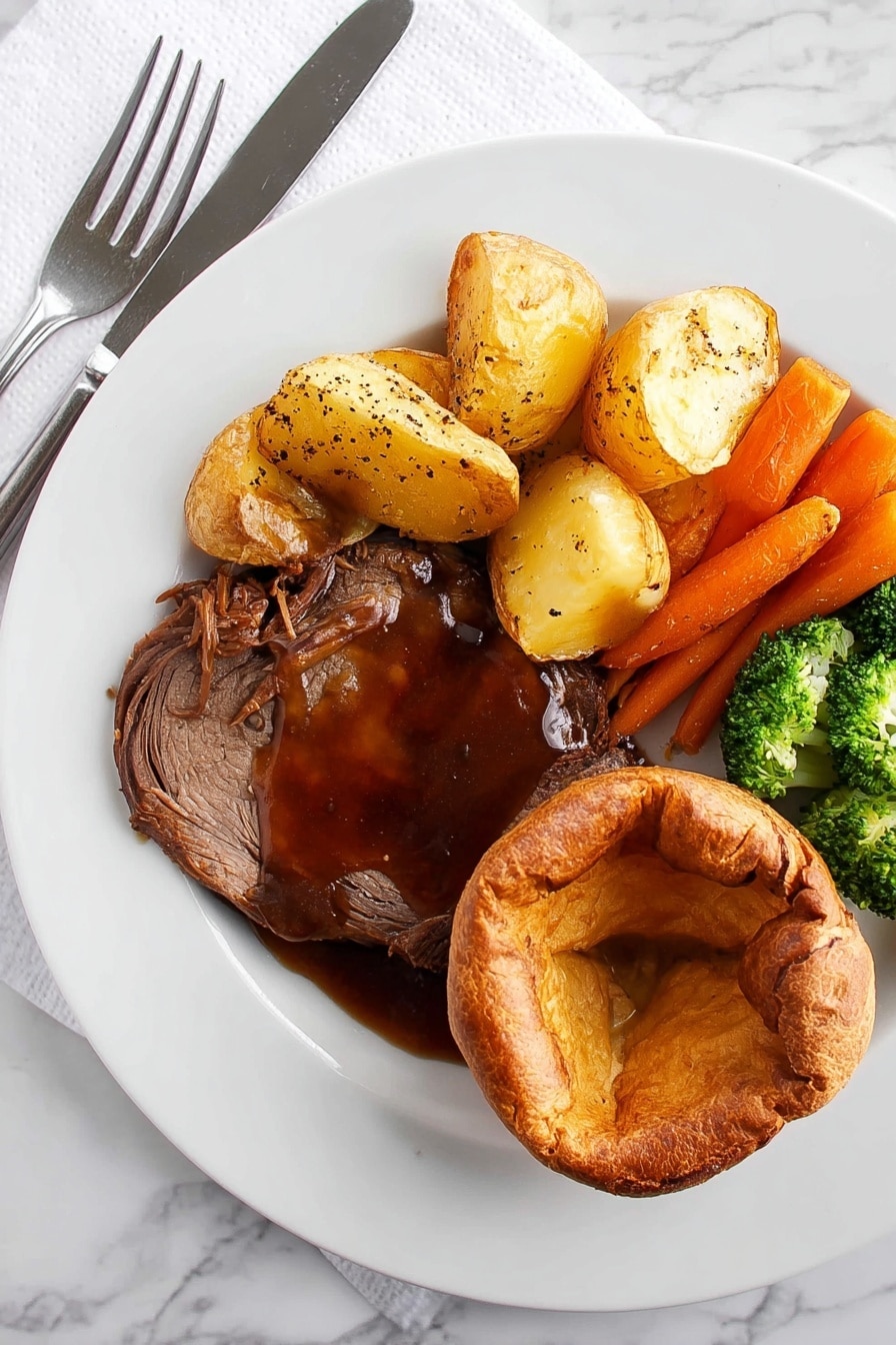A white plate on a white marbled surface holds a meal with four parts. On the bottom right is a golden brown round Yorkshire pudding with a soft, slightly folded center. Next to it on the left is a thick slice of dark brown roast meat covered in rich, shiny brown gravy sprinkled with coarse black pepper. Above the meat are several light golden roast potatoes with a crispy surface. To the left of the potatoes is a mix of bright orange whole baby carrots and green broccoli florets with a slight shine, showing they are cooked but still fresh. A knife and fork rest on the left side of the plate on a white napkin. Photo taken with an iphone --ar 2:3 --v 7 - Yorkshire Pudding, Perfect Yorkshire Pudding, Classic Yorkshire Pudding, Easy Yorkshire Pudding Recipe, British Yorkshire Pudding