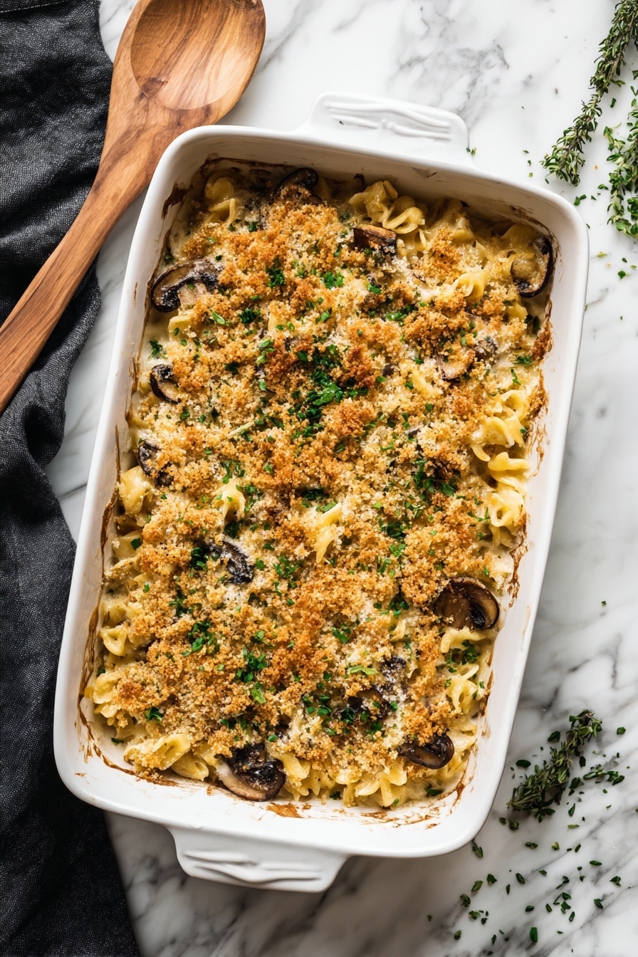 The image shows a white bowl filled with a baked pasta dish consisting of three layers. The bottom layer is light beige penne pasta mixed with cooked dark green spinach. The middle layer reveals slices of browned mushrooms that sit on top of the pasta and spinach mix. The top layer is a golden-brown crispy breadcrumb topping, sprinkled unevenly with some light green herbs for garnish. A silver fork rests on the right side of the bowl. In the background, there is a white baking dish containing the same layered pasta, with a wooden spoon partially submerged in it. The scene is set on a white marbled surface, providing a clean and bright contrast to the dish. Photo taken with an iphone --ar 2:3 --v 7 - Creamy Mushroom Kale Pasta Bake, mushroom kale pasta casserole, hearty mushroom kale pasta, cheesy vegetable pasta bake, easy healthy pasta recipes