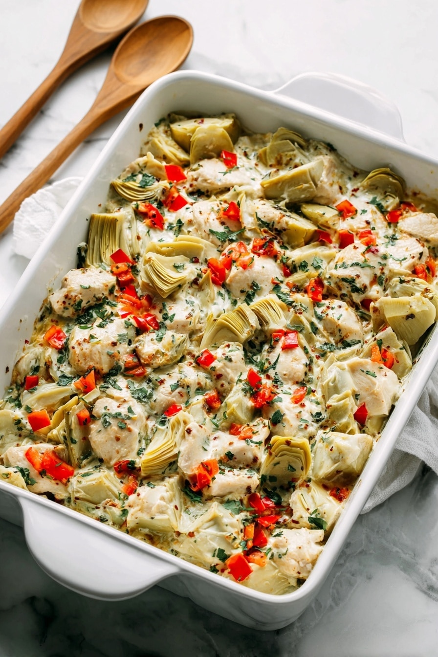 A white rectangular baking dish filled with a layered mix of creamy white sauce, pieces of light beige cooked chicken, and quartered pale green artichoke hearts. The dish is sprinkled with small, bright red bell pepper pieces and finely chopped dark green herbs, creating a colorful contrast. The textures range from creamy sauce to tender chunks of chicken and soft artichokes, all blended evenly across the dish. The dish sits on a white marbled surface with two wooden spoons with white handles placed behind it. Photo taken with an iphone --ar 2:3 --v 7 - Spinach Artichoke Chicken Bake, creamy chicken bake with spinach and artichokes, easy chicken dinner recipes, one-pan chicken dish, healthy chicken bake ideas