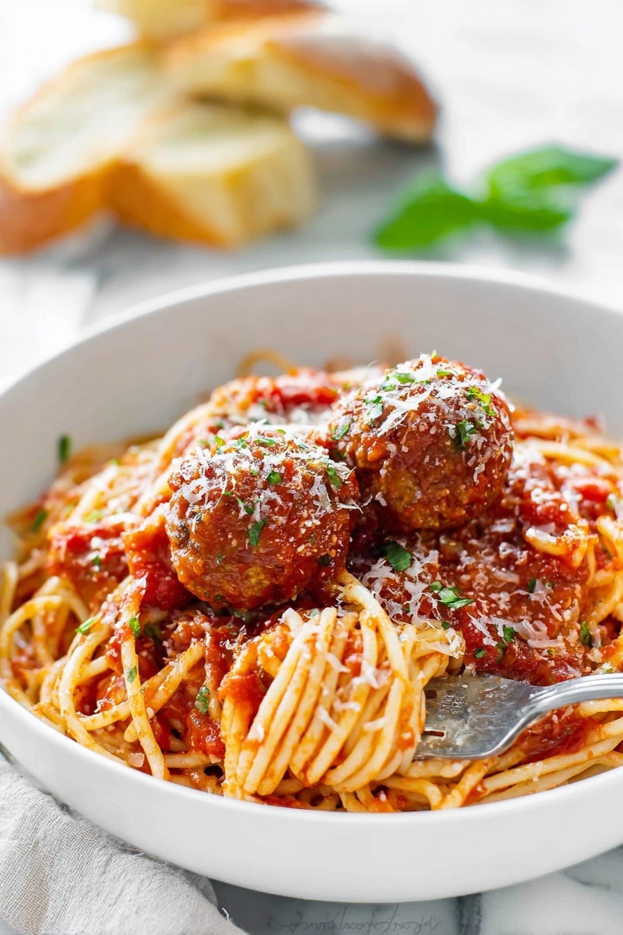 A large red pot holds a mix of spaghetti and meatballs in a rich tomato sauce. The spaghetti is long and golden, twisted around and soaked in the chunky red sauce. The meatballs are round and brown, scattered evenly through the noodles, some partially covered with sauce. A wooden spoon with a smooth light wood texture is stirring the pasta, with some sauce on it. The pot’s inside edge shows a coating of the thick tomato sauce. The background has a white marbled texture. photo taken with an iphone --ar 2:3 --v 7 - Homemade Spaghetti and Meatballs, Italian pasta with meatballs, easy spaghetti and meatballs, classic Italian spaghetti dish, homemade marinara and meatballs